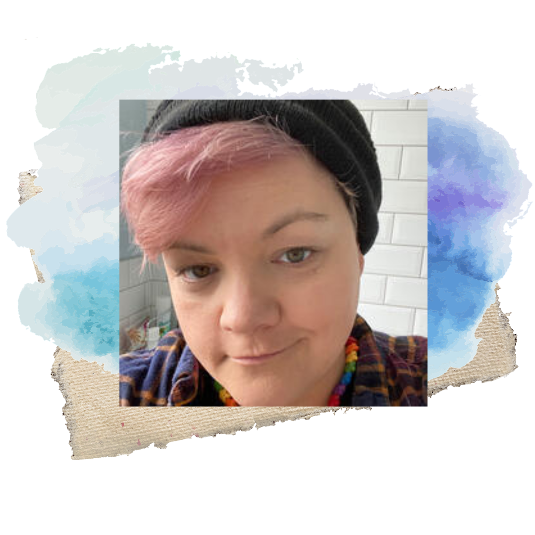 Close-up selfie of a person with pink hair, wearing a black beanie and a colourful necklace, smiling gently, with a blue watercolour wash background.