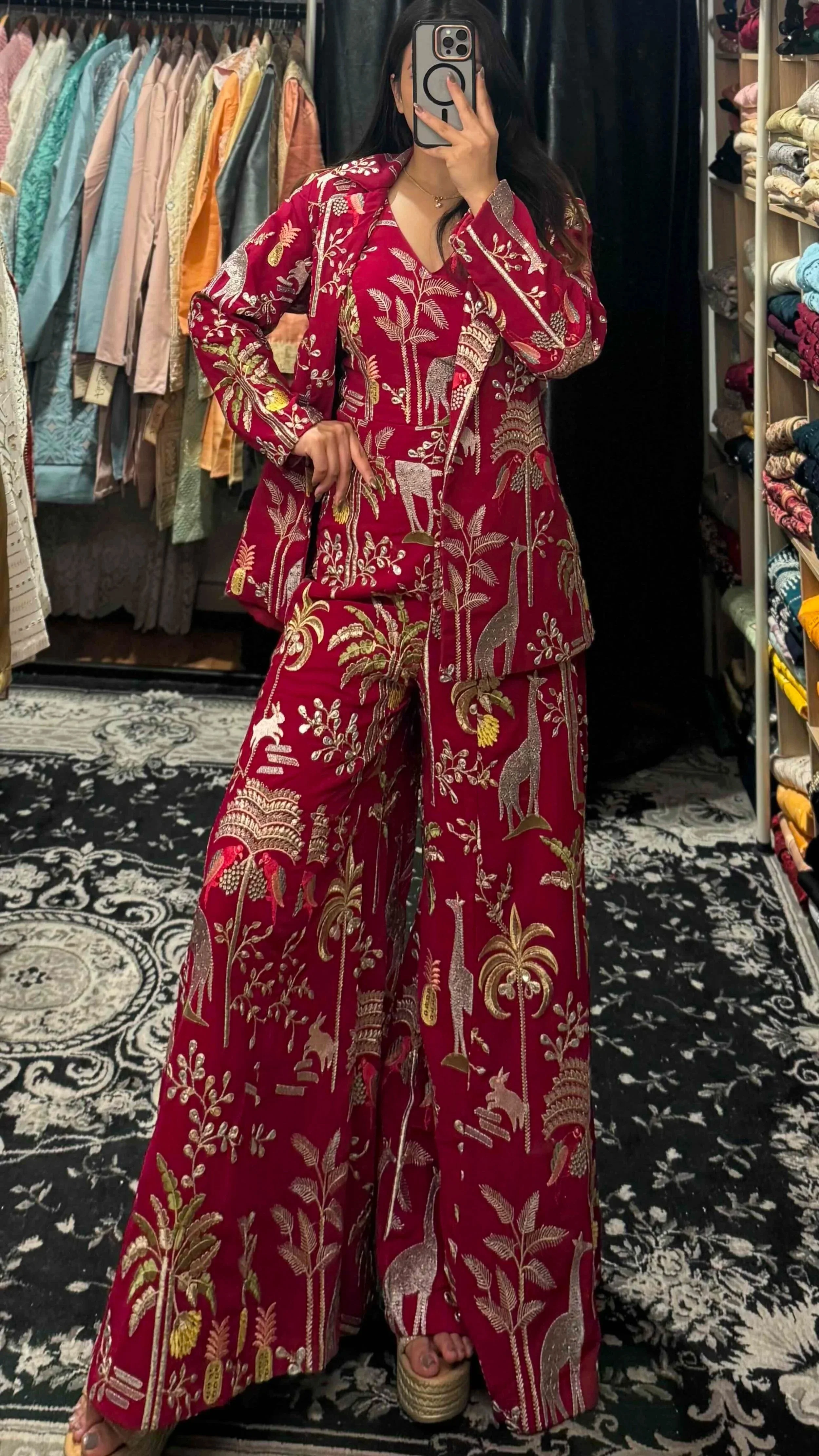 Close-up of intricate zardozi embroidery with giraffe, bird and palm tree motifs on maroon jumpsuit