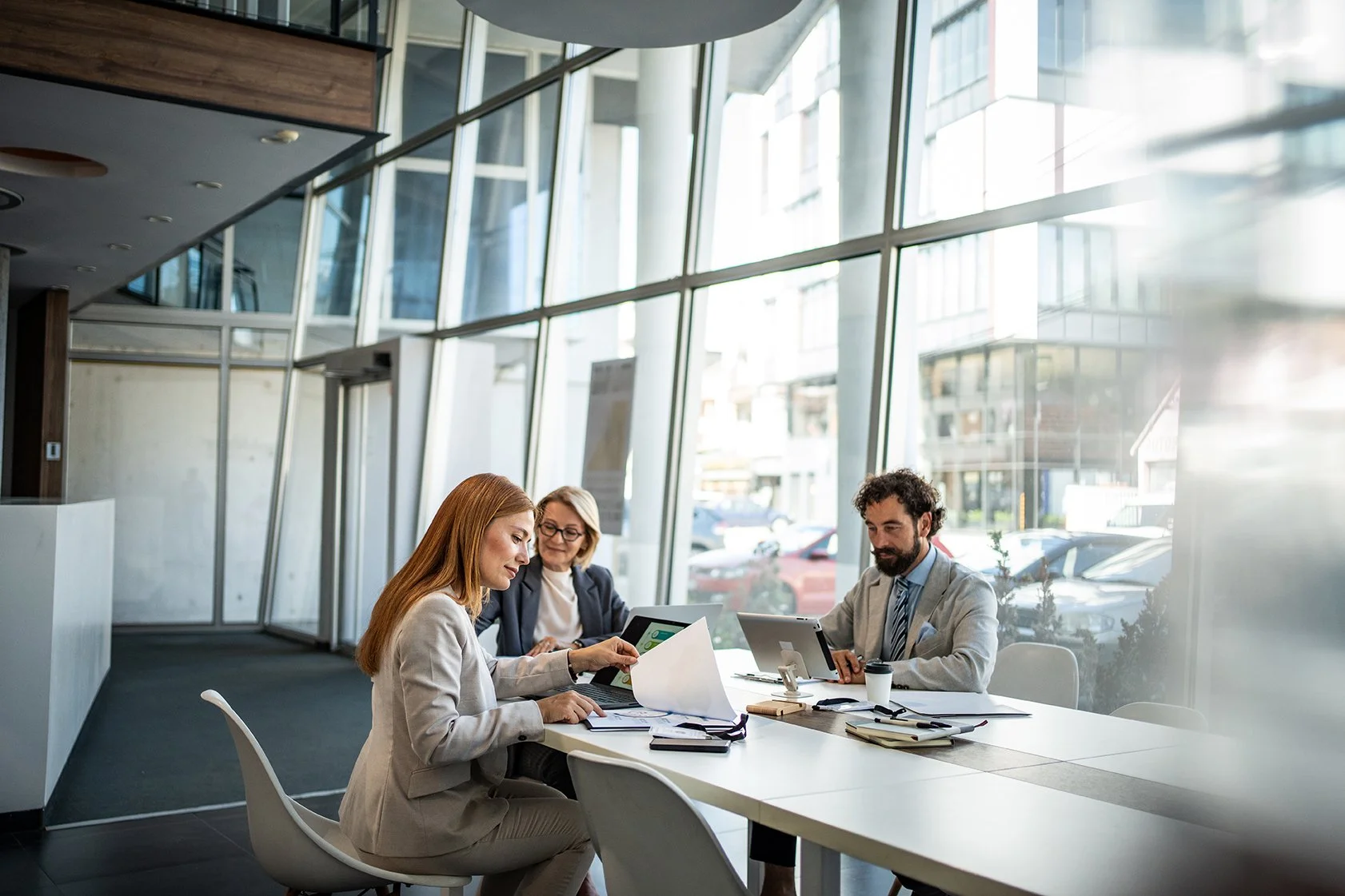 2 Frauen und 1 Mann sitzen an einem Tisch und arbeiten