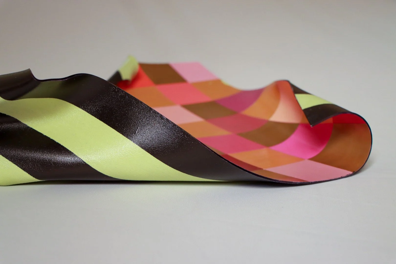 Close-up of a pastel-colored ribbon with a checkered pattern, black with bright yellow stripes, curled and resting on a light surface.