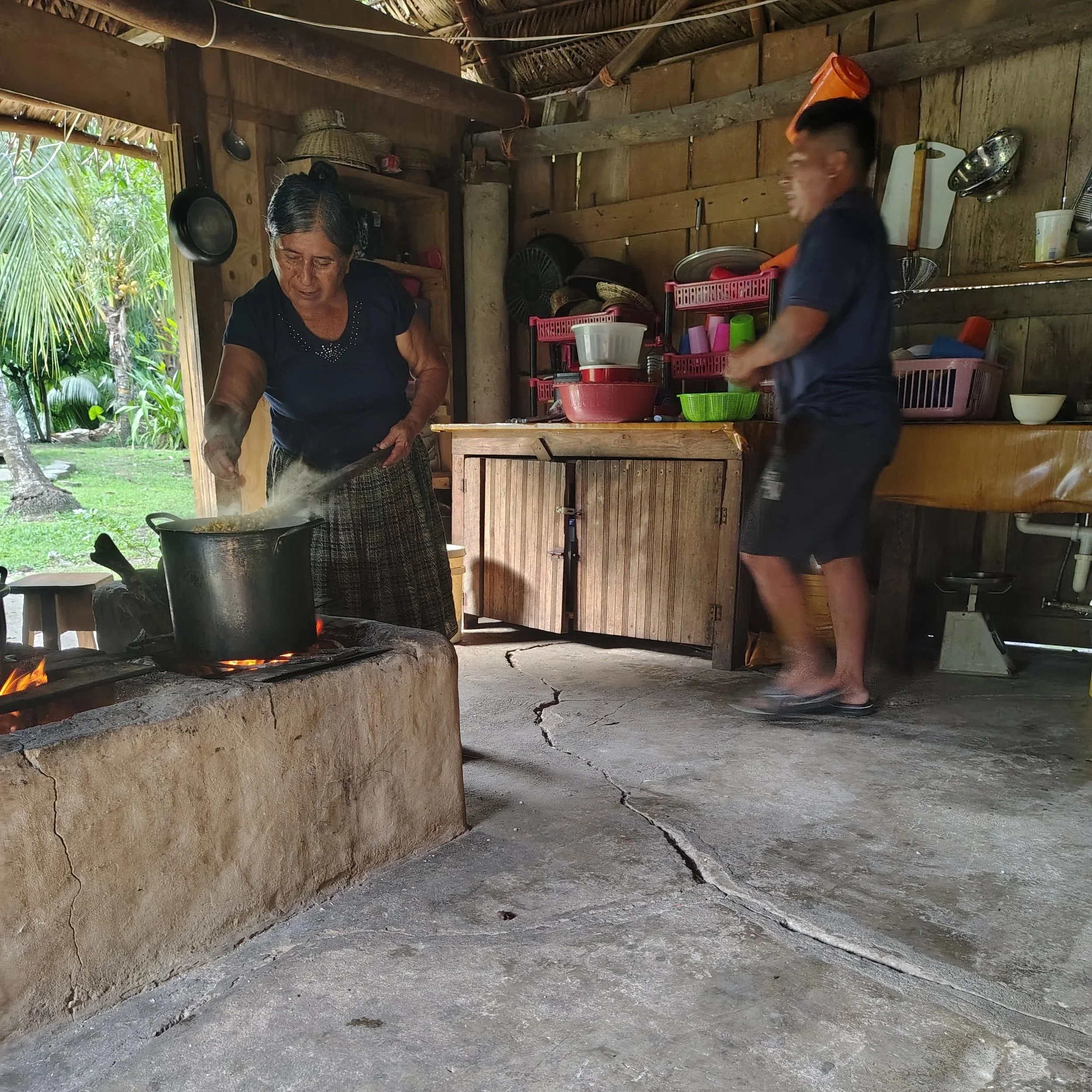 Mrs. Makin preparing a pot of corn for tortillas on the fire in the kitchen.