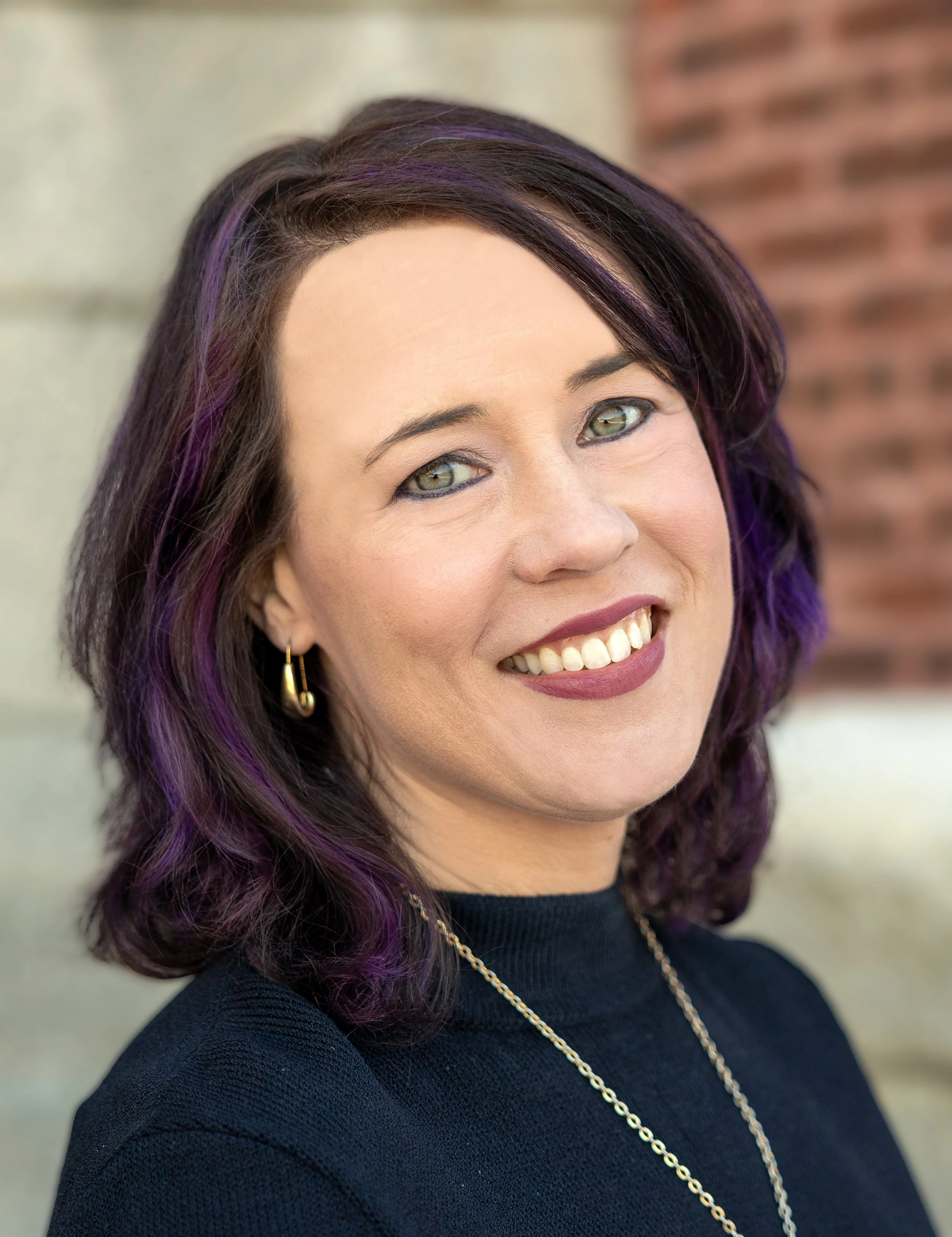 Julie Hulburd, a woman with dark hair and purple highlights smiling at the camera.