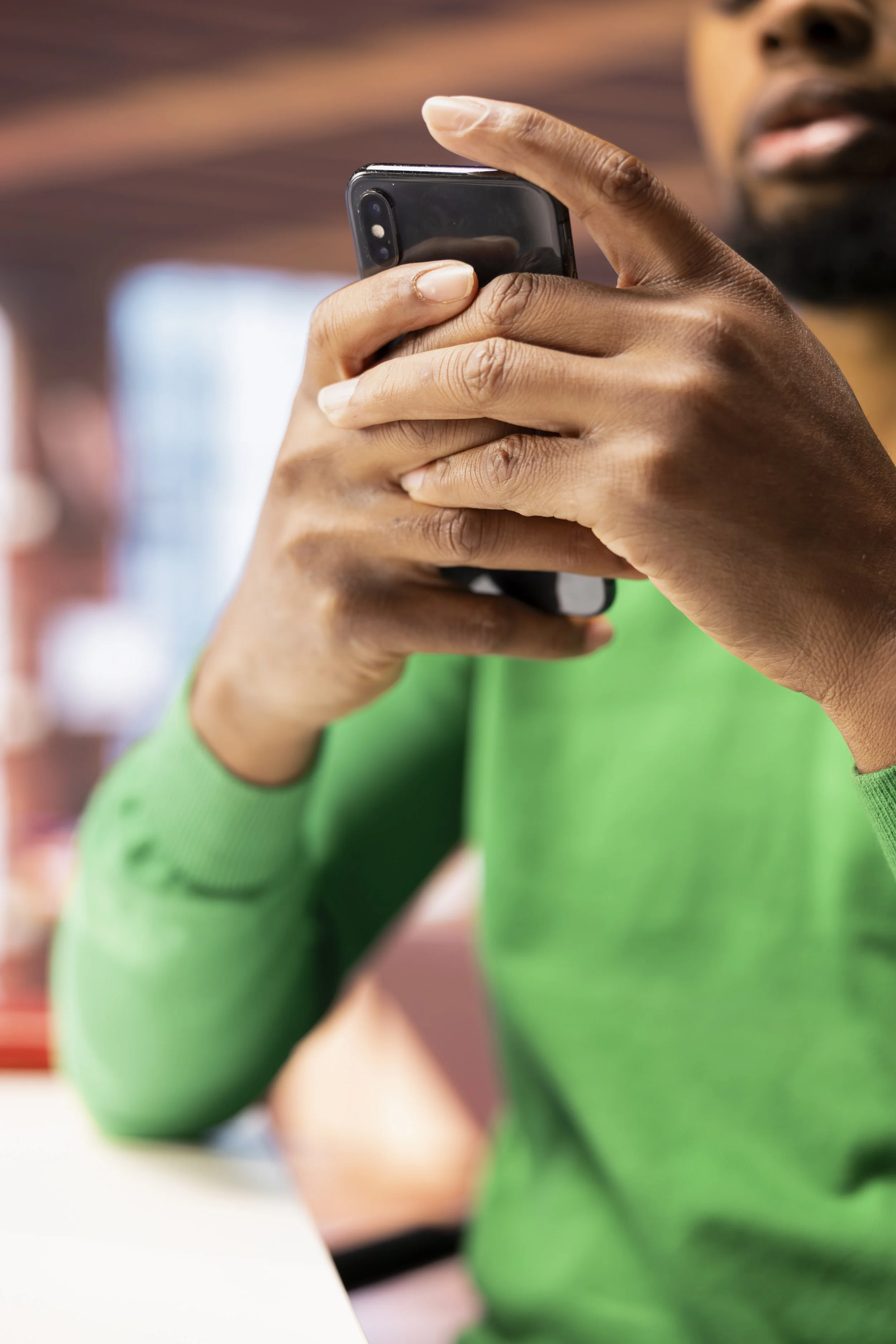 Person in green shirt holding and looking at smartphone