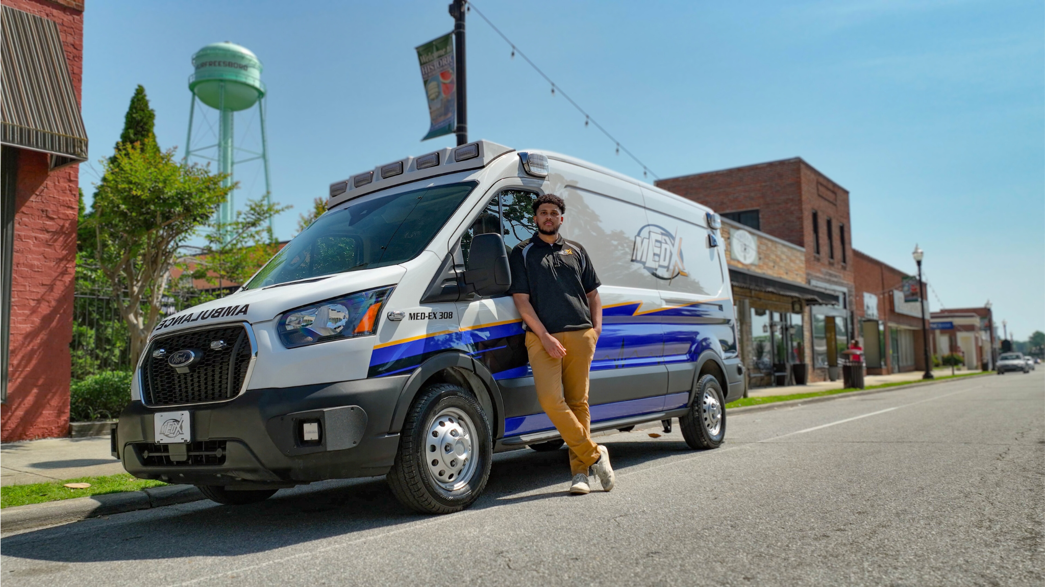 Young man standing beside an ambulance parked on a city street.