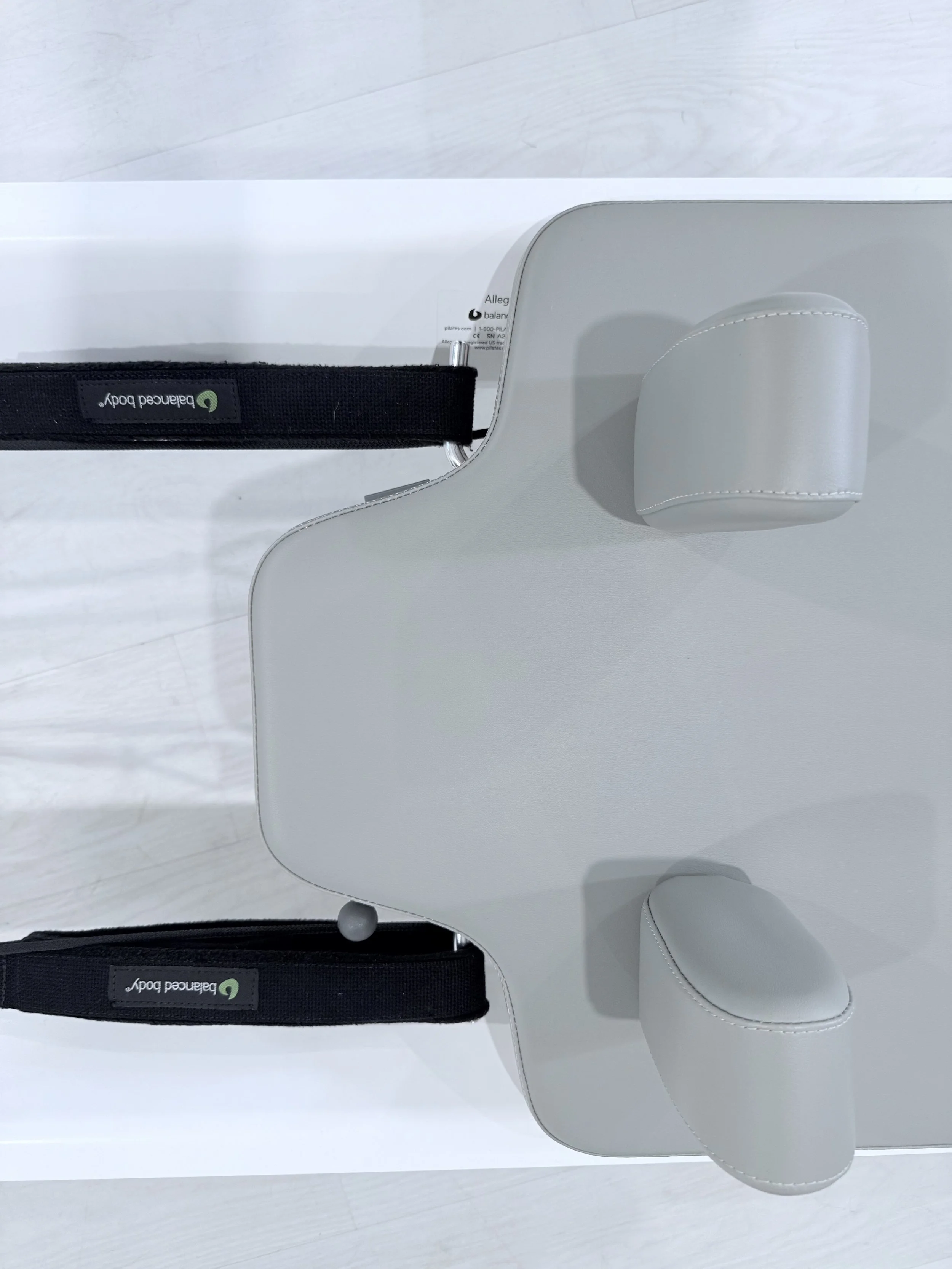 Top view of a white medical or therapy device with two padded sections and black straps labeled 'Balanced Body'.