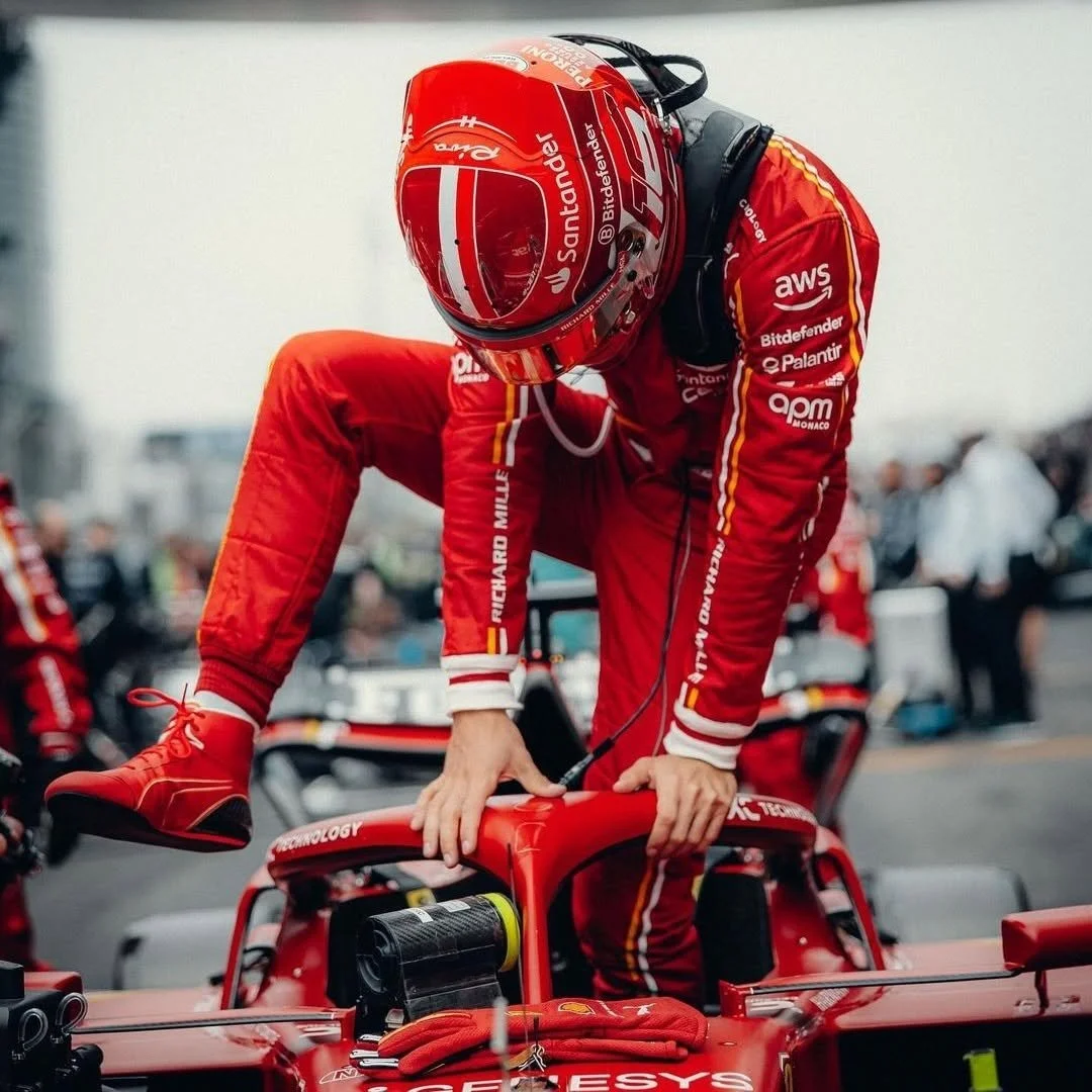 Pilote de course en combinaison rouge et casque intégral en train de monter dans une voiture de course de Formule 1