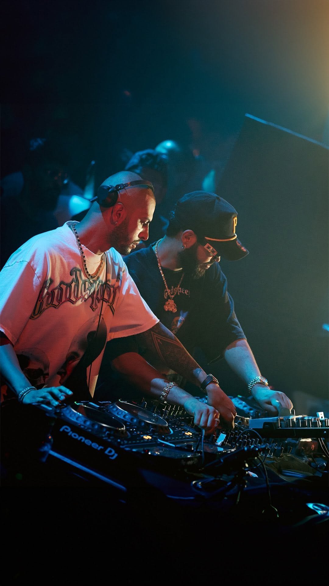 Deux DJ avec des équipements de musique en plastique case, jouant dans une boîte de nuit sombre avec des lumières colorées.