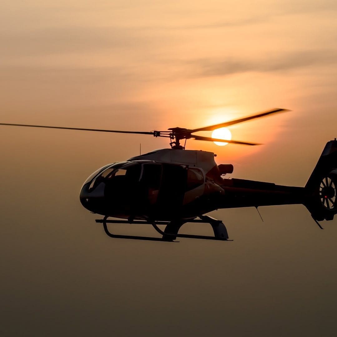 Un hélicoptère en vol lors du coucher de soleil, avec le soleil derrière la hélice.