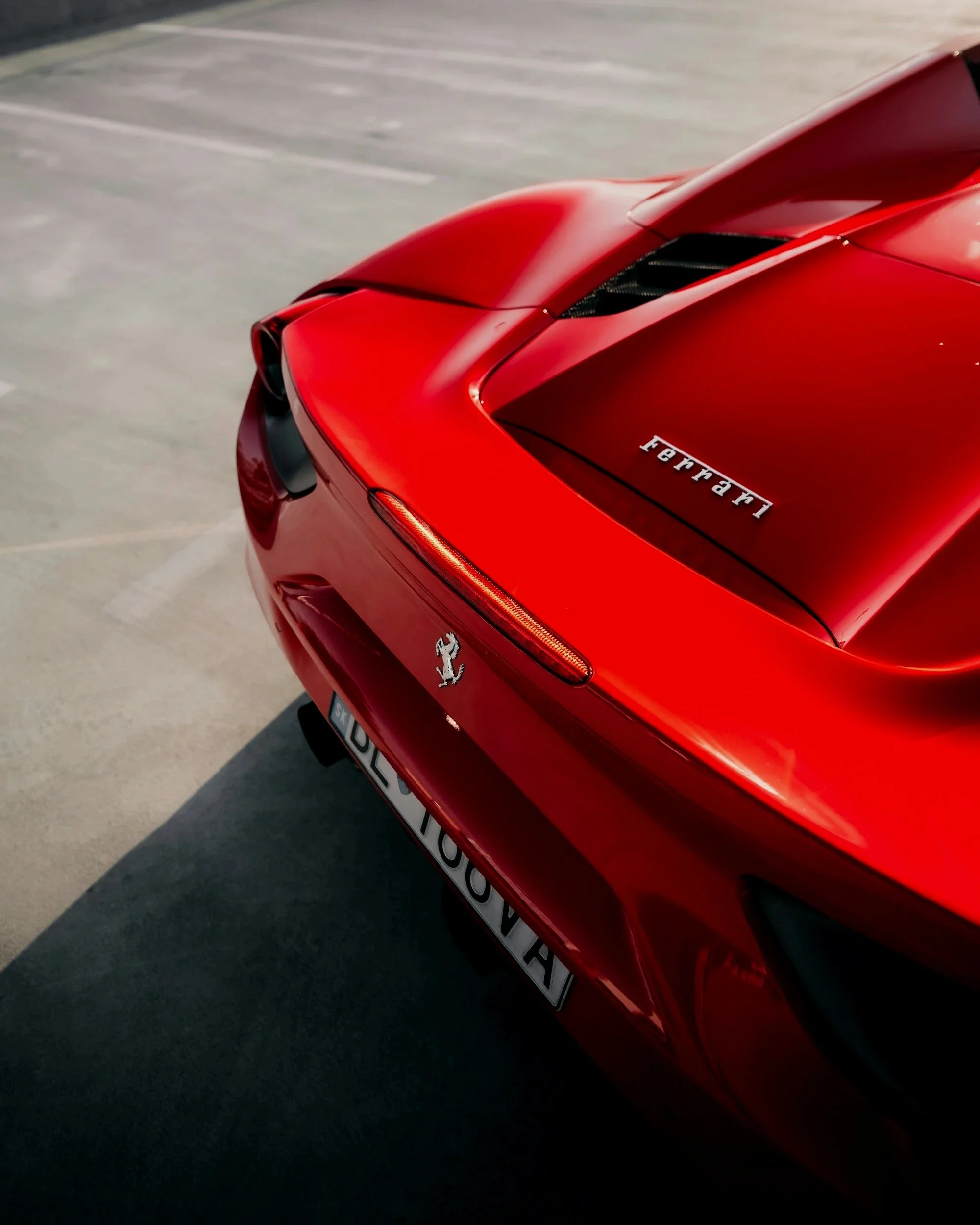 Voiture Ferrari rouge vue de l'arrière dans un parking.