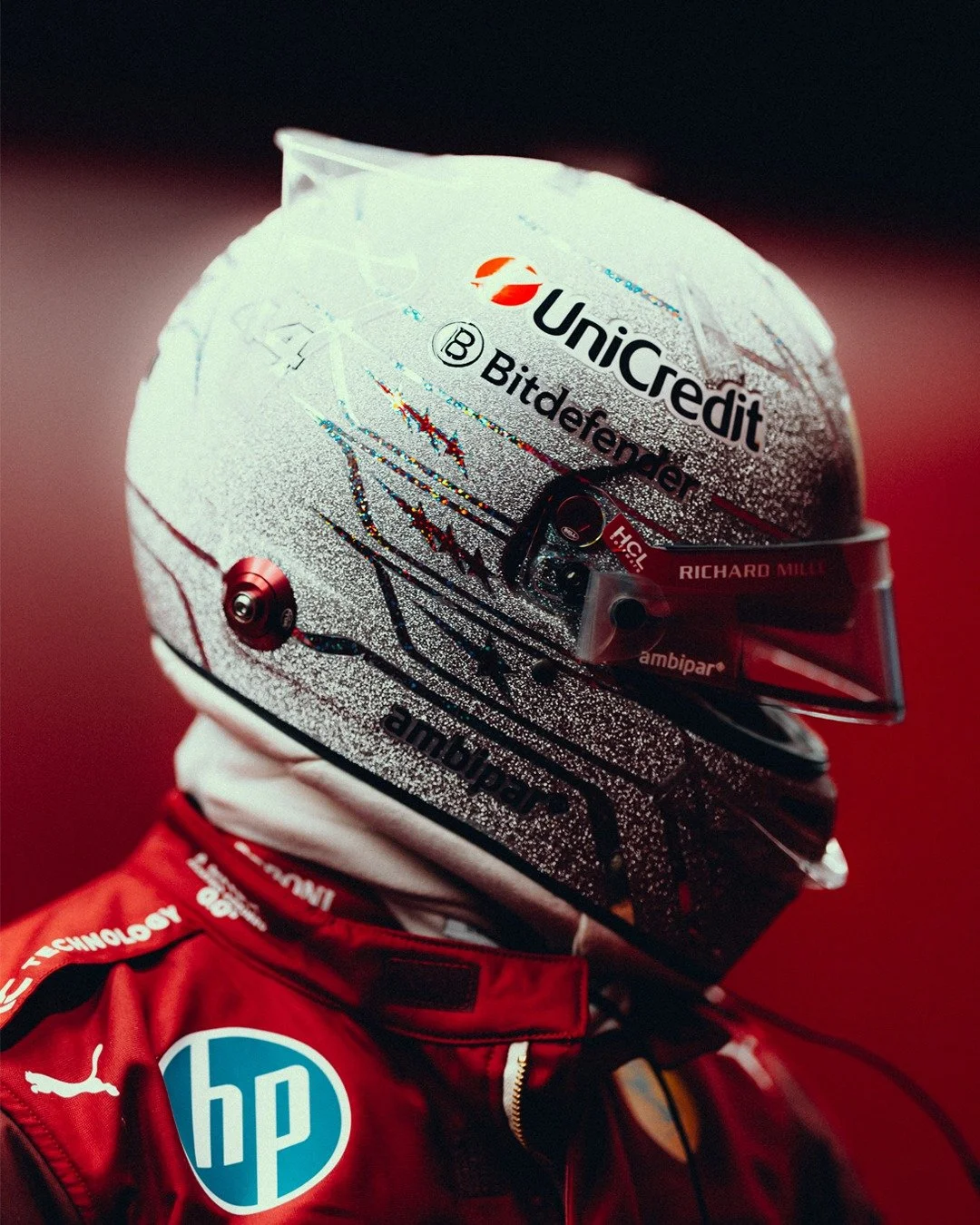 Un casque de pilote de course avec des sponsors et un design complexe, porté par une personne en combinaison rouge.