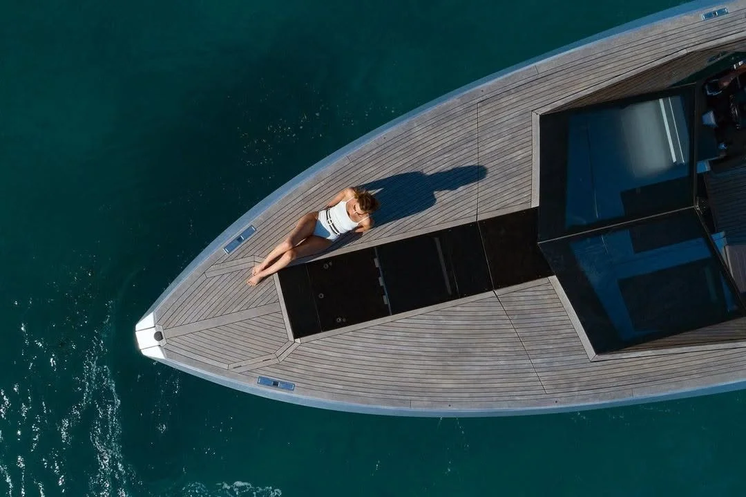 Une personne allongée sur le pont en bois d'un yacht, vue aérienne.