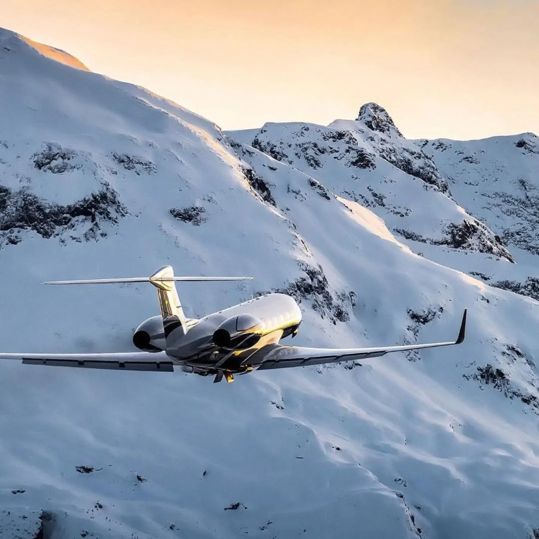 Un jet volant dans un paysage de montagnes enneigées au coucher du soleil.