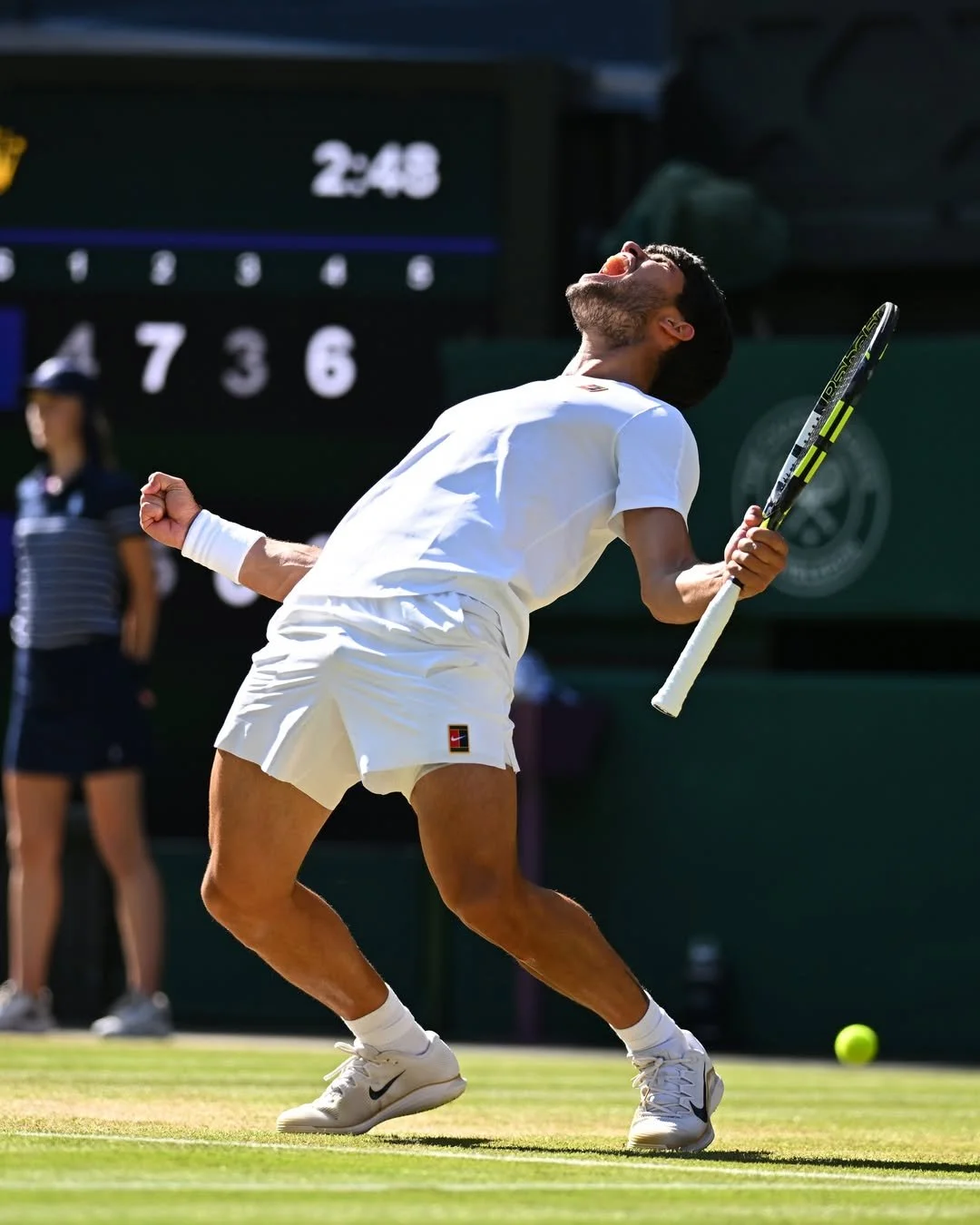 Un joueur de tennis en tenue blanche célèbre sa victoire sur le court, avec un geste de triomphe, lors d'un match.