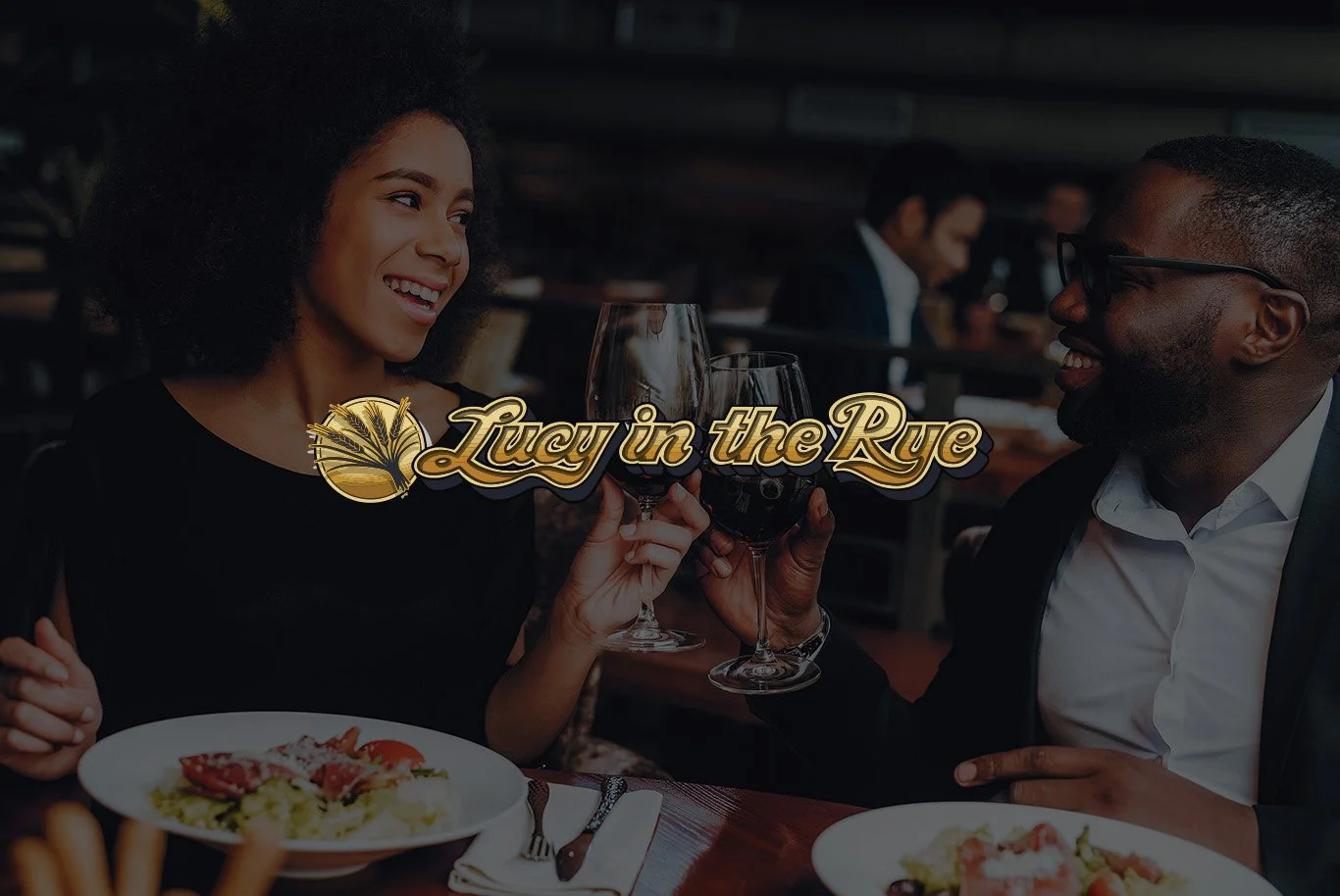 A woman and man toasting with glasses of red wine at a dinner table in a restaurant, smiling at each other.