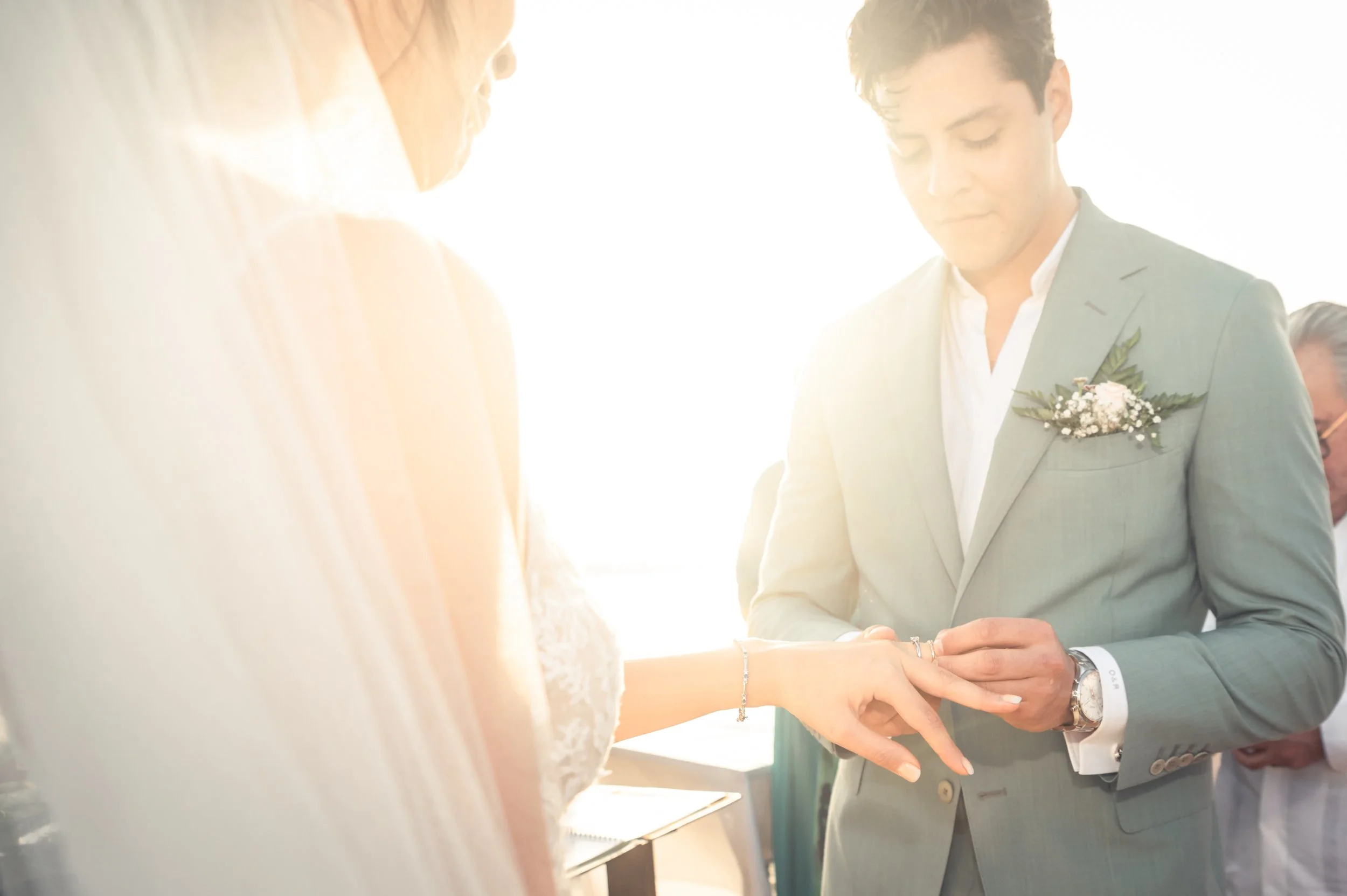 Exchange of ring during a wedding ceremony in Puerto Escondido. Luxurious suit of the groom with nice floral composition.