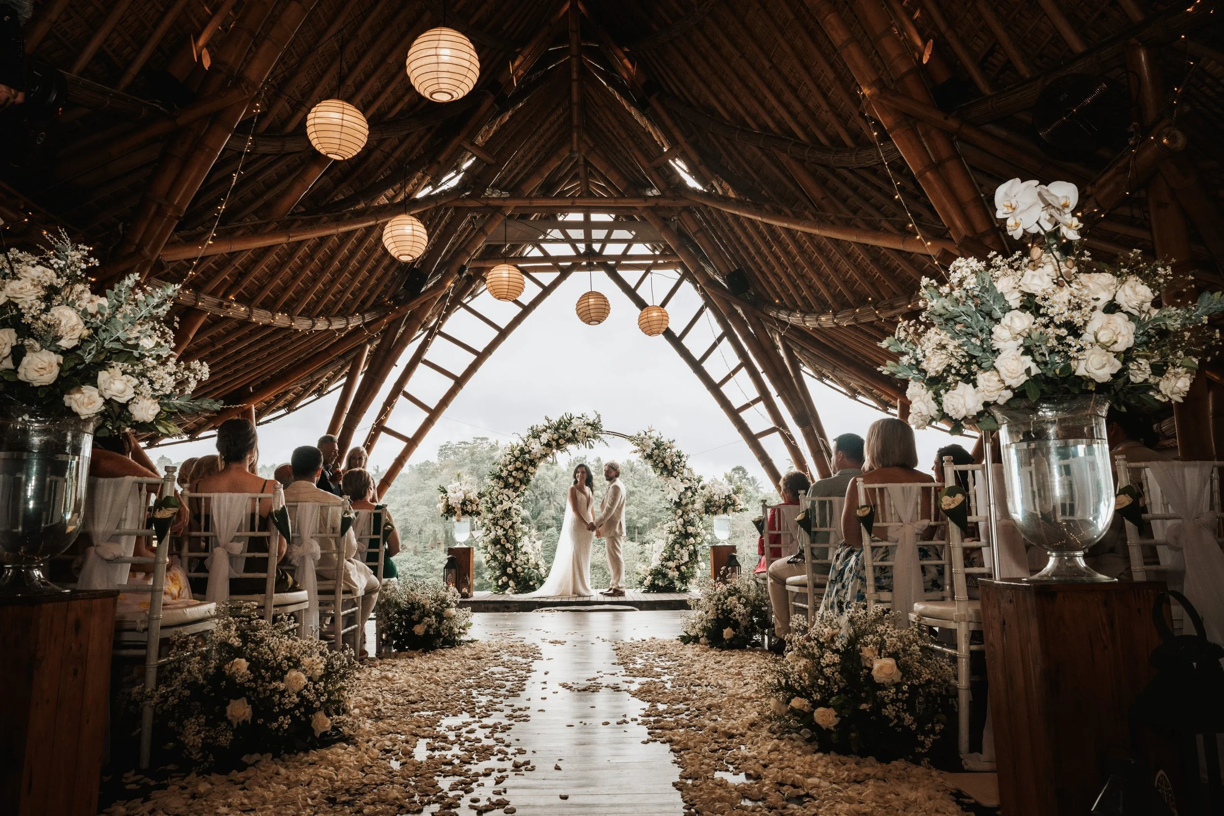 Bali destination wedding ceremony — intimate vow exchange on a private cliffside terrace in Ubud's jungle valley. luxurious bamboo structure 