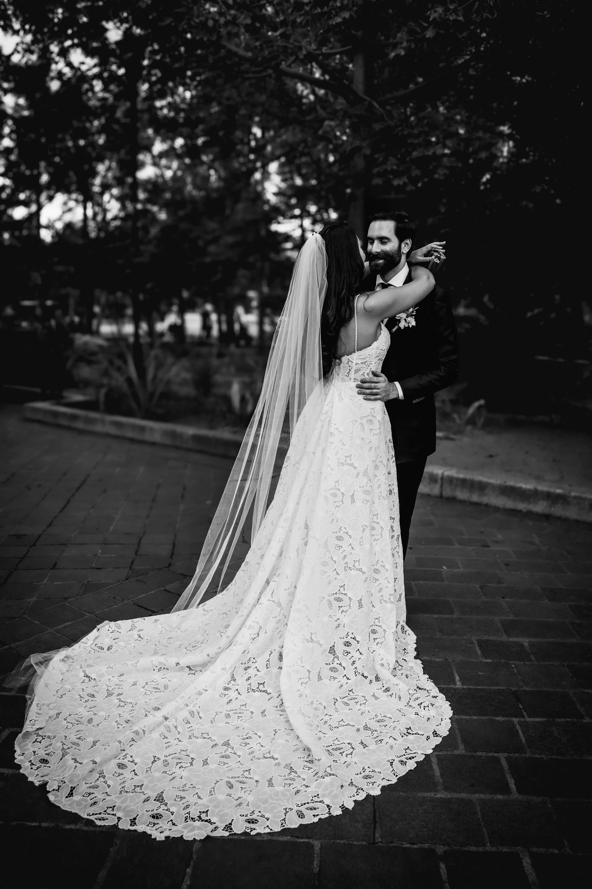 Black and white photo of a maried couple standing in an Oaxacan park with the tree behind. Oaxaca wedding photography
