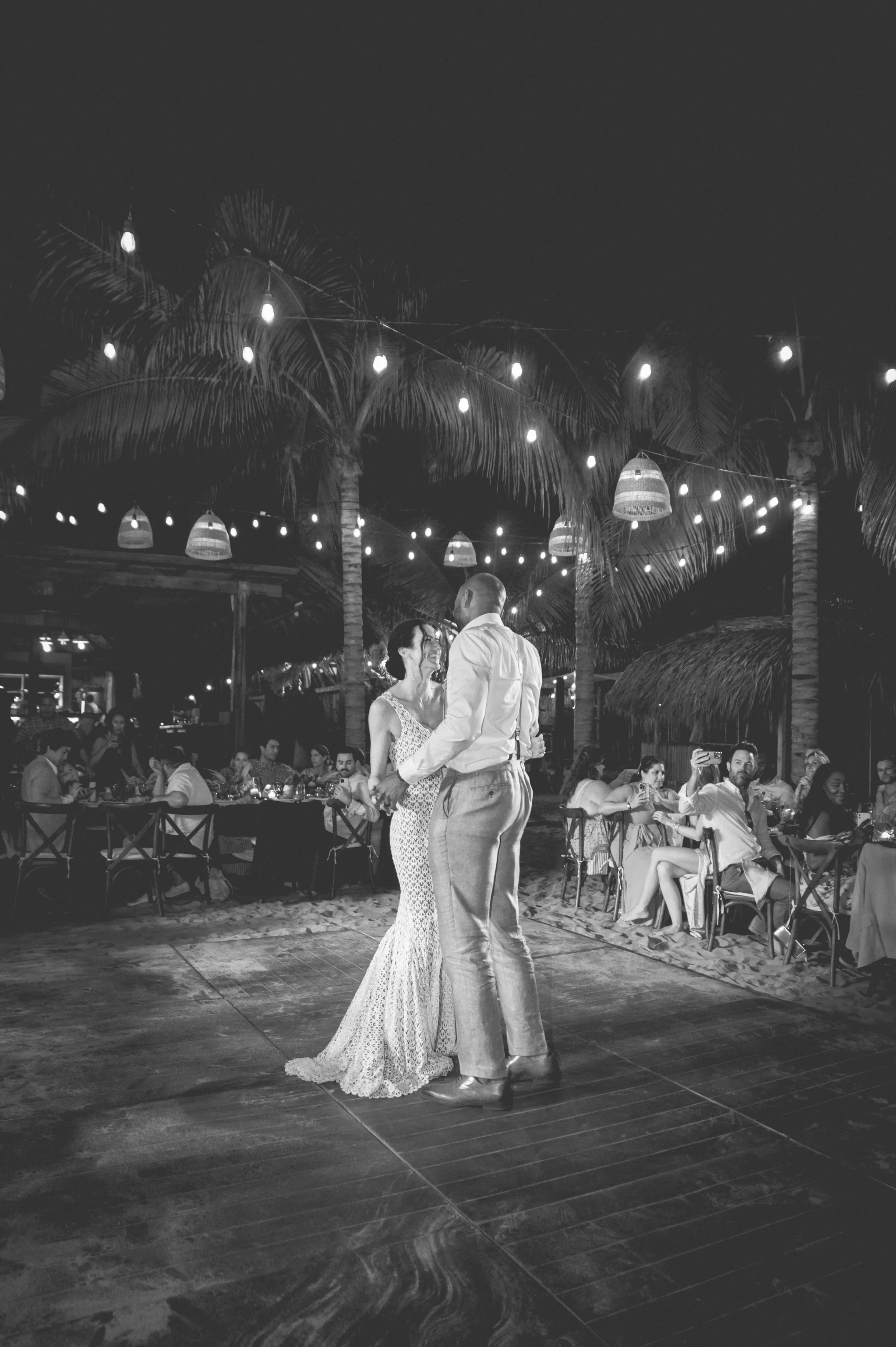 Black and white photography of a maried couple dancing in their wedding party in the middle of the dancing floor with all their guest around them. Very happy vibes in a luxurious Villa in Puerto Escondido