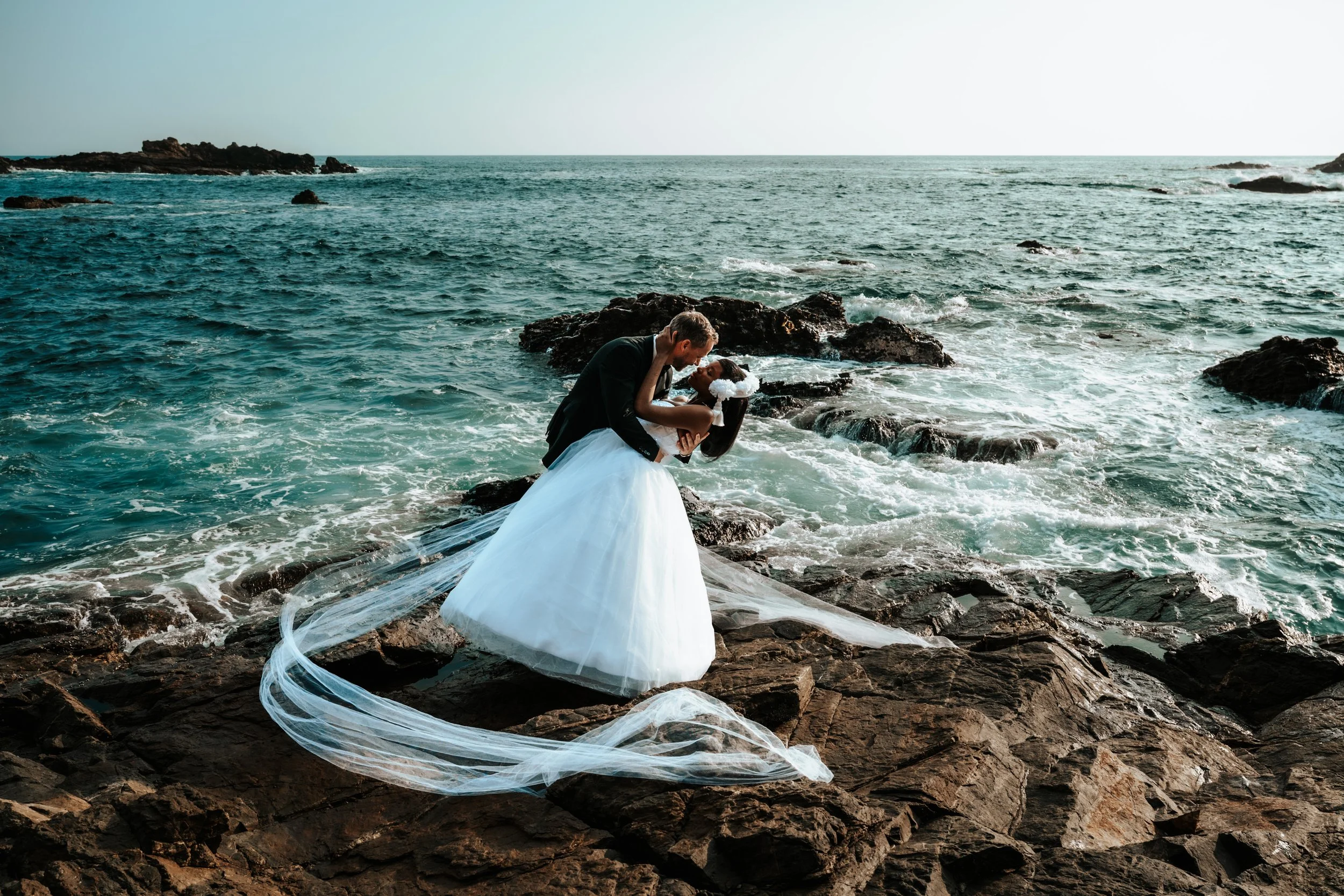 Editorial destination wedding photography in Mazunte, capturing a couple embracing on oceanfront rocks in a moment of calm, luxury, and connection.