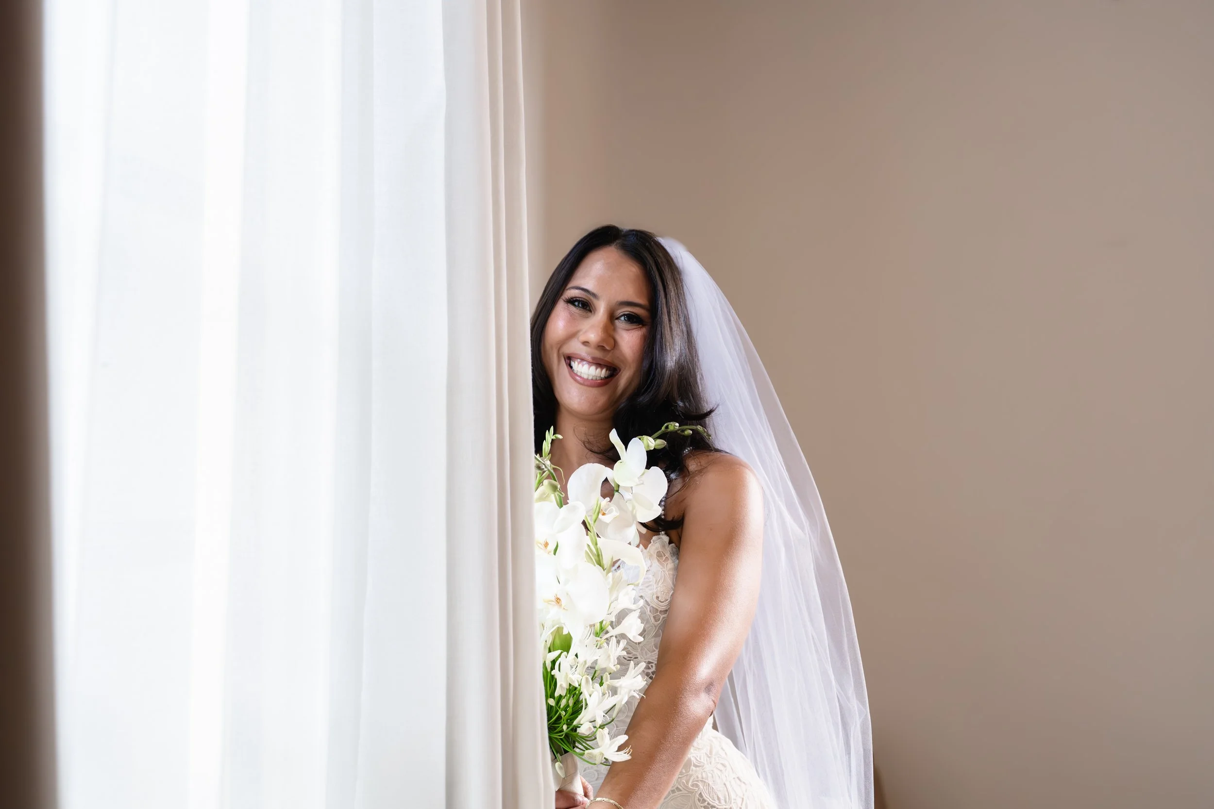 Bride with flower composition standing in front of a windows smiling at the camera