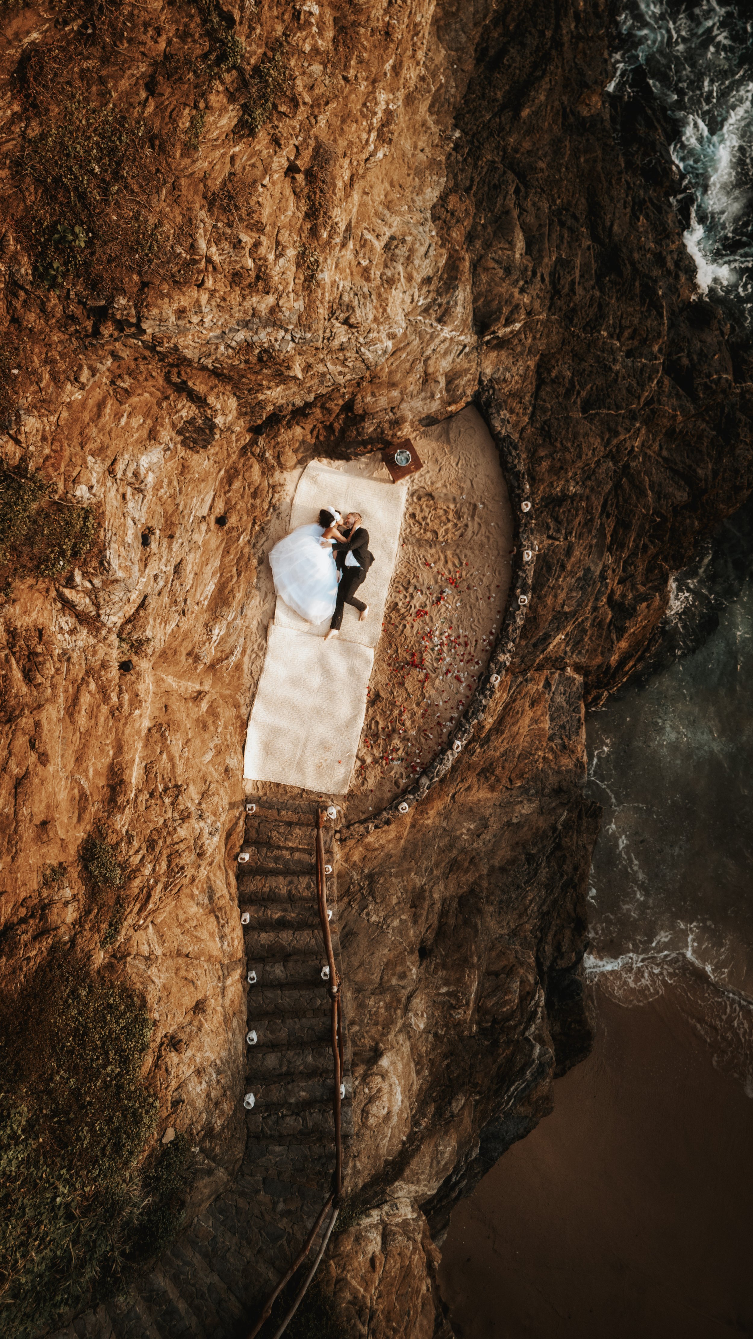 Luxury destination wedding photography in Mazunte, created for couples seeking elegance, intimacy, and authenticity in Mexico. drone shot from hotel Zoa of a maried couple laying near the ocean.