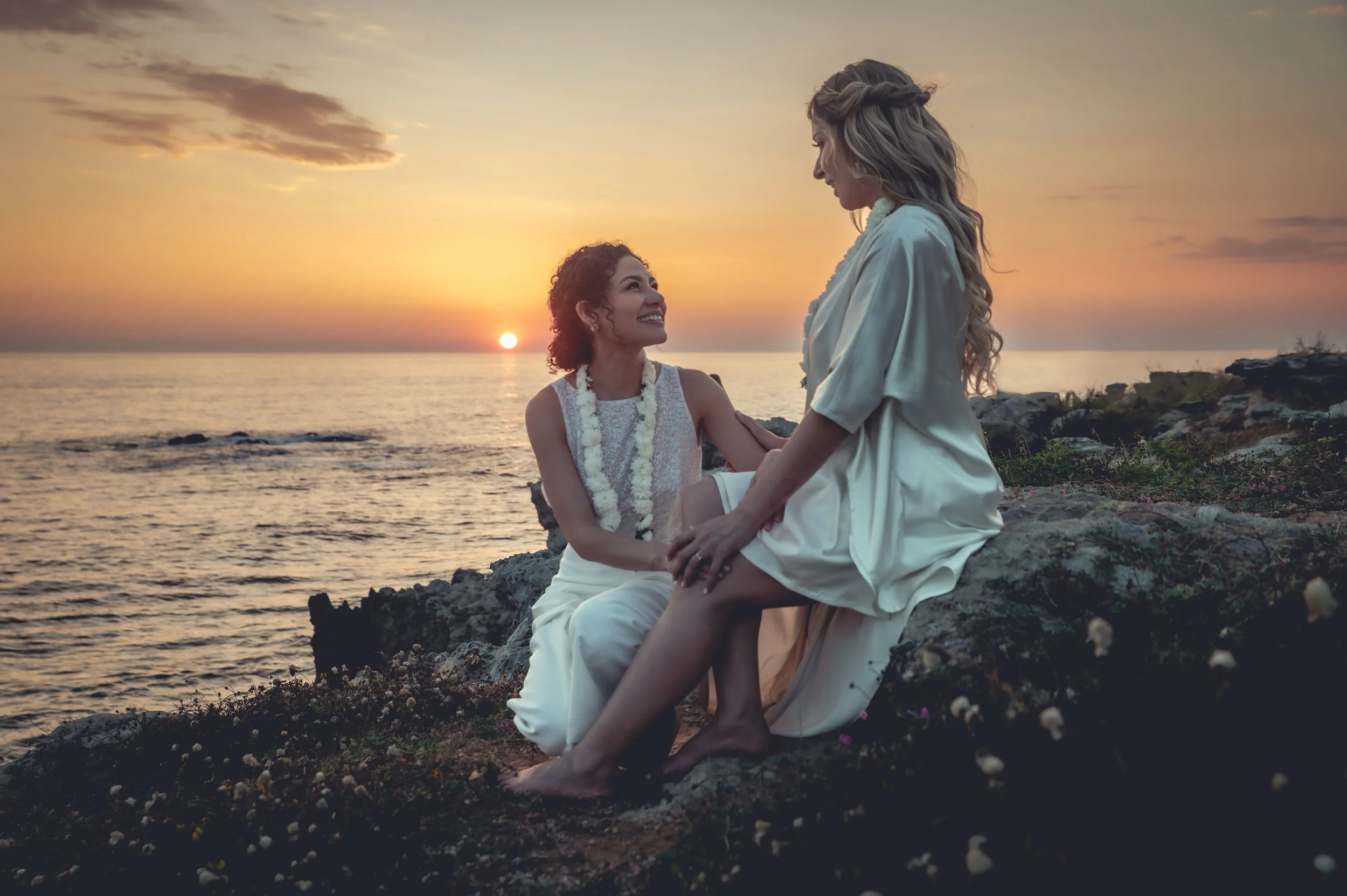LGBT wedding in Puerto Escondido of two brides in looking at each other in beautiful white dress, holding hands,  looking each other with love,  beautiful sunset in Puerto Escondido.