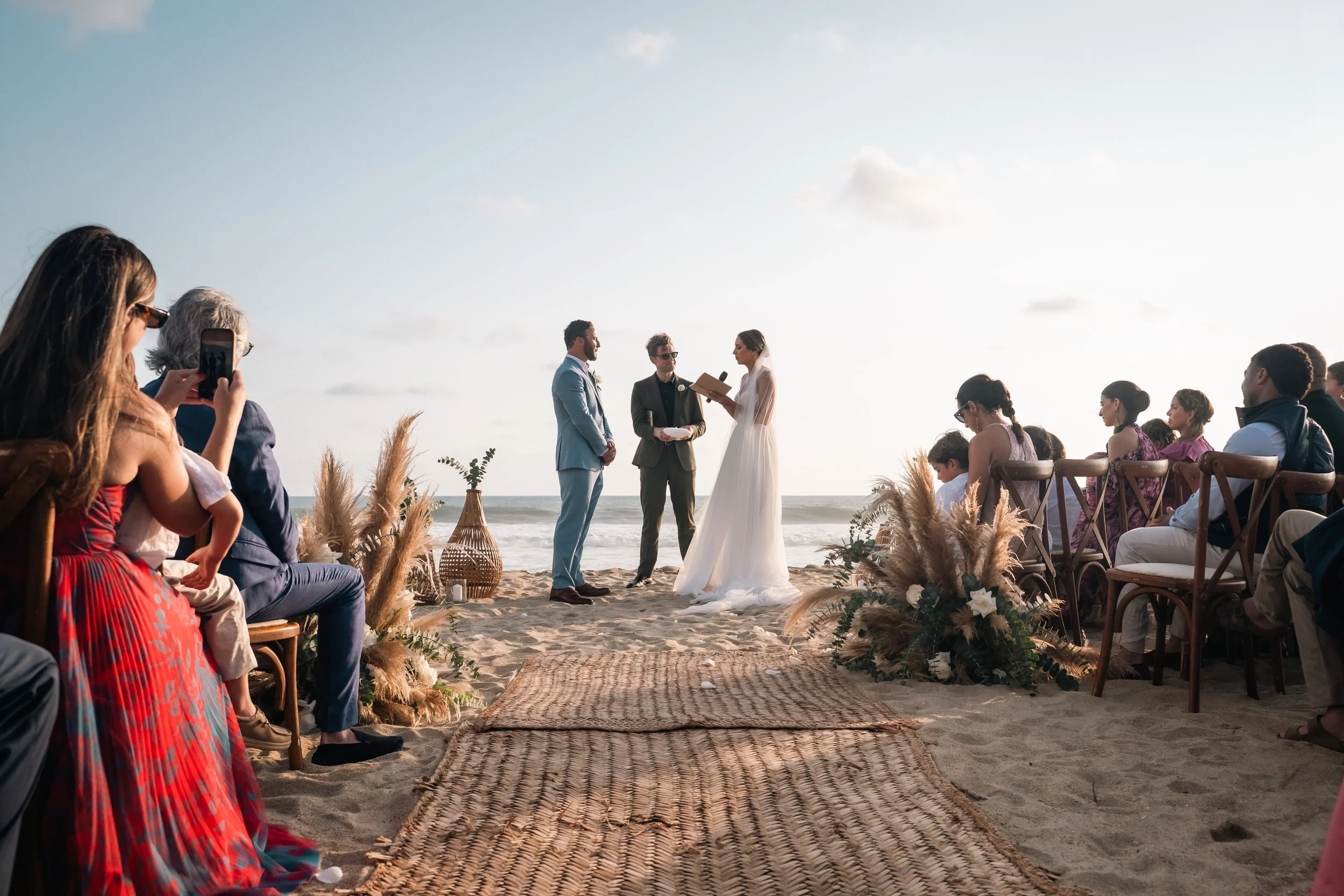 Sunset moments during a destination wedding in Puerto Escondido, captured at a private luxury villa for an American couple. Sharing vows during the ceremony of a maried couple.