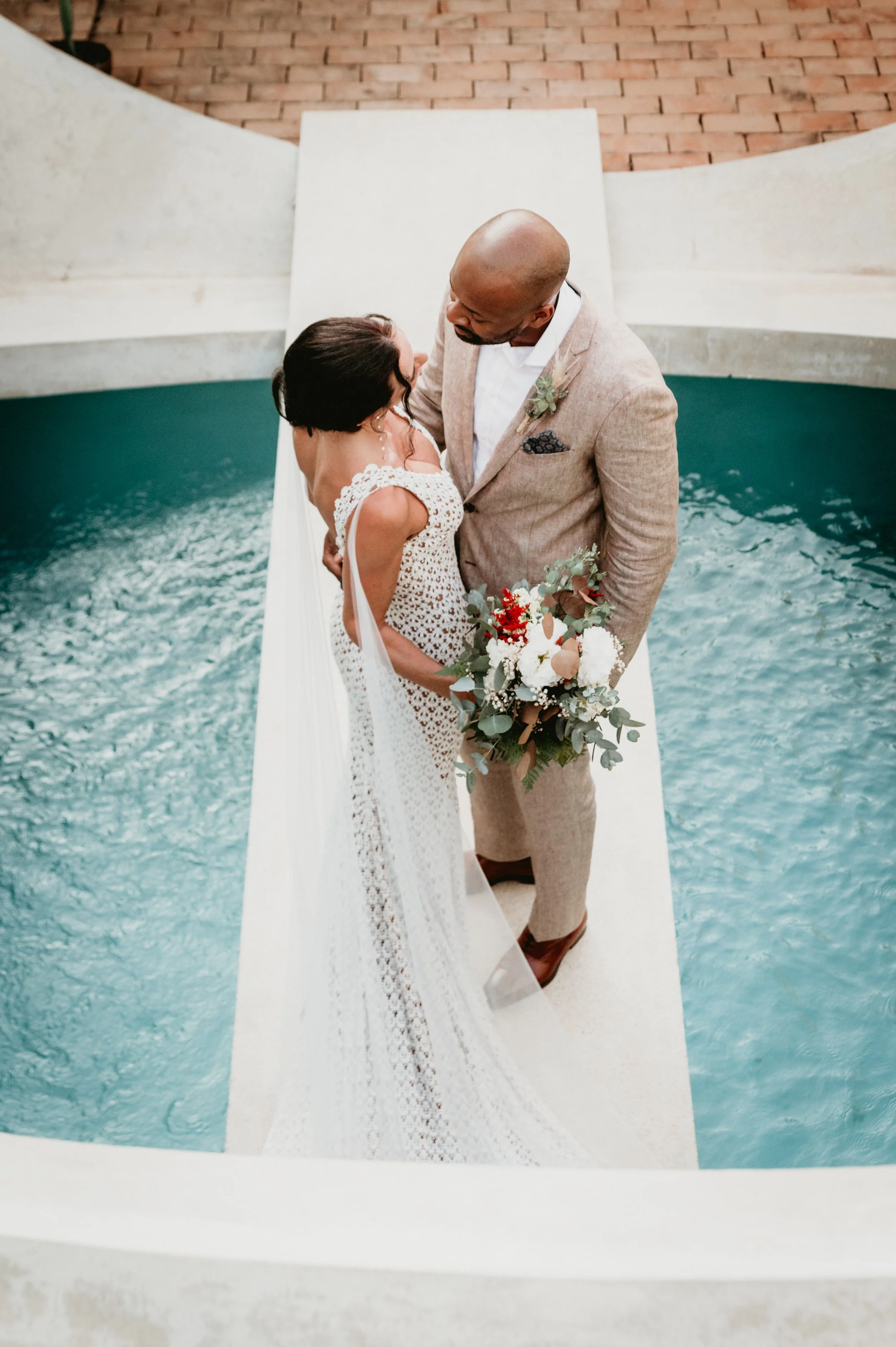 Maried Couple looking at each other on a bridge over luxurious pool in puerto escondido.