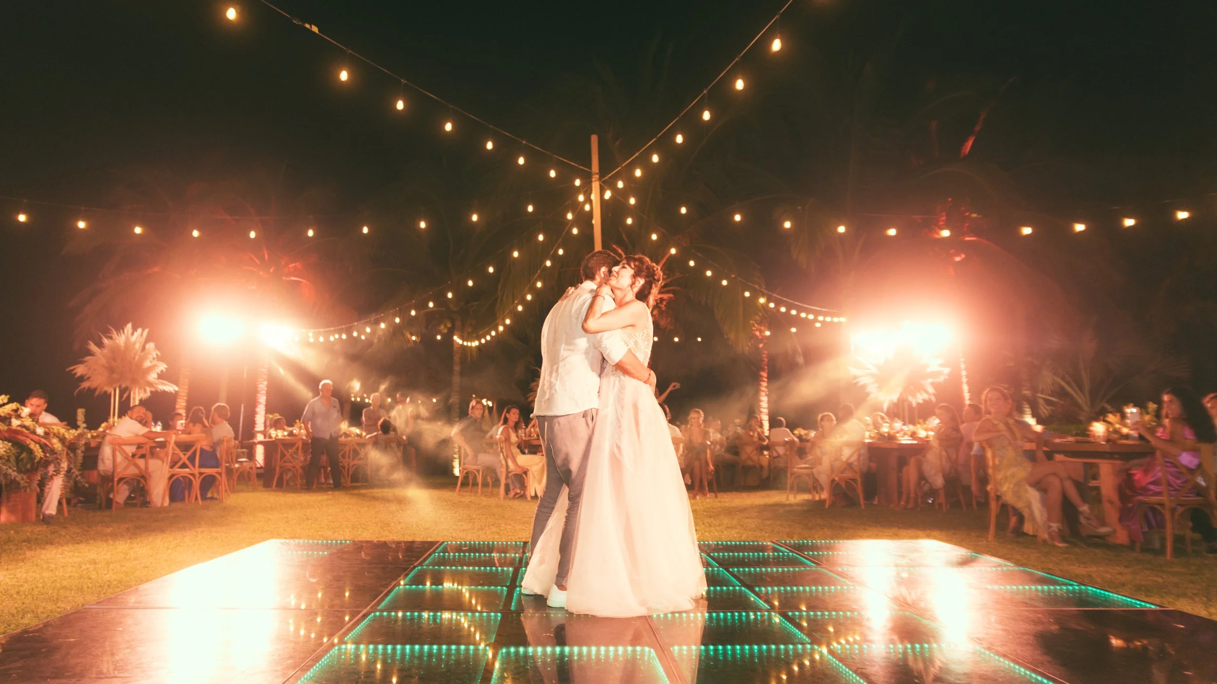 Maried couple dancing in their wedding party in the middle of the dancing floor with all their guest around them. Very happy vibes and colorfull. nice light beam in luxurious Villa in Puerto Escondido