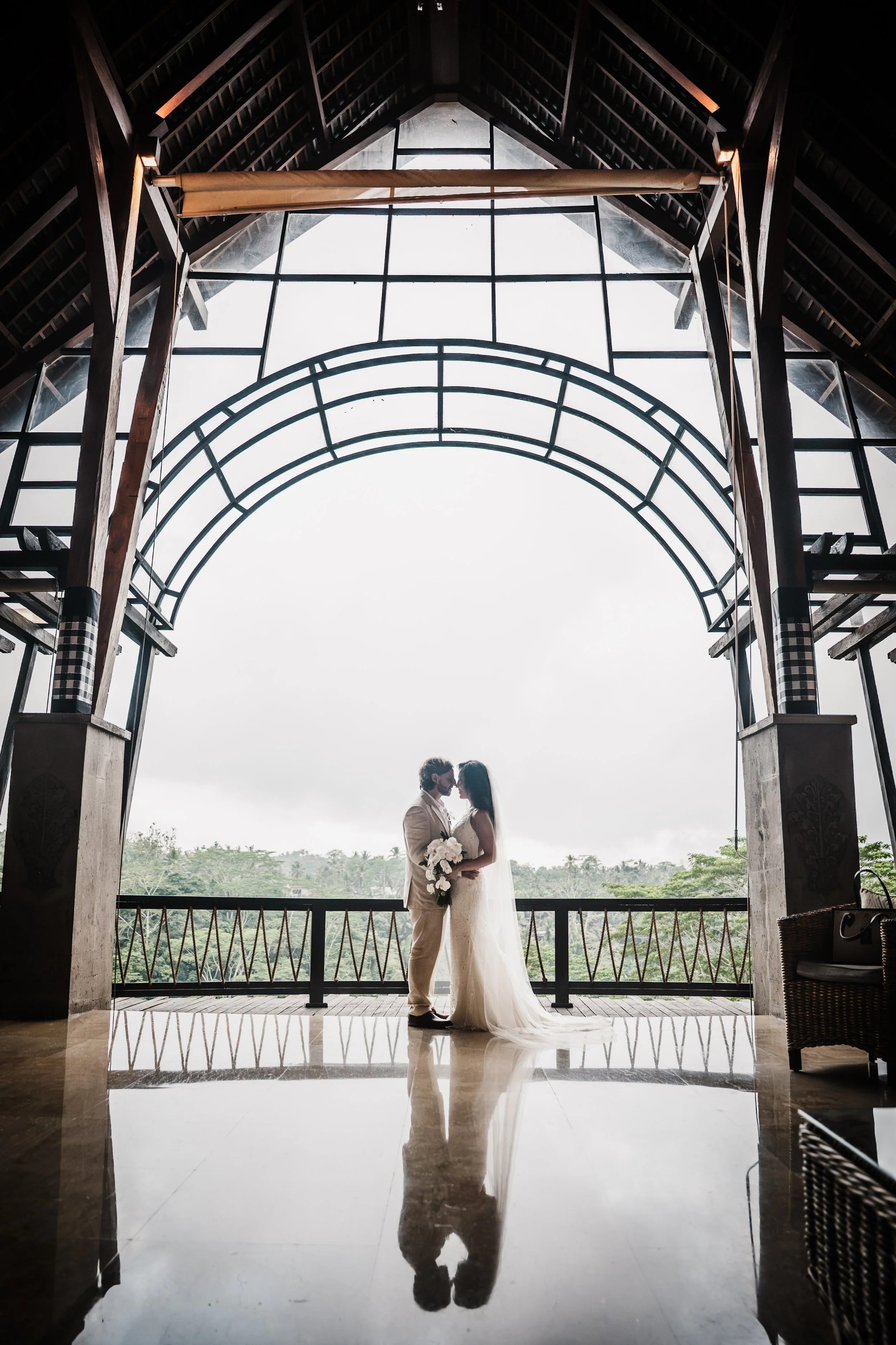Ubud jungle resort bridal portraits — bride & groom reflection against dense tropical greenery and river canyon backdrop. church structure