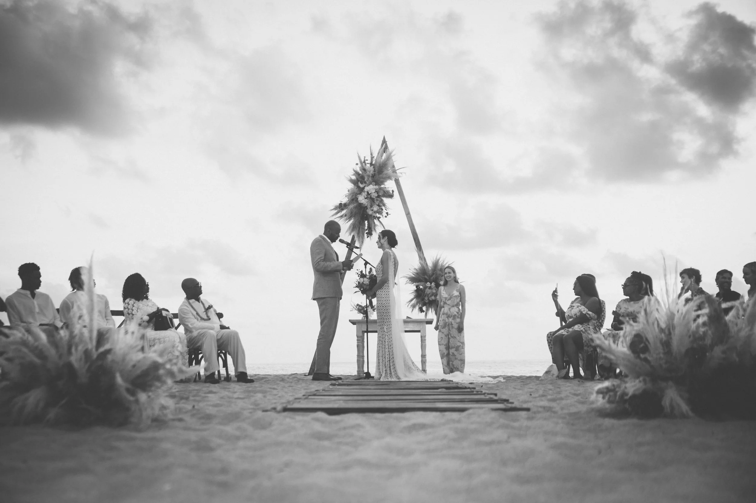Wedding ceremony in Puerto Escondido where an american couple from San Francisco are exchanging their vows in front a beautiful sunset at the beach in Puerto Escondido. Amazing frame and luxurious wedding dress. black and white photography.