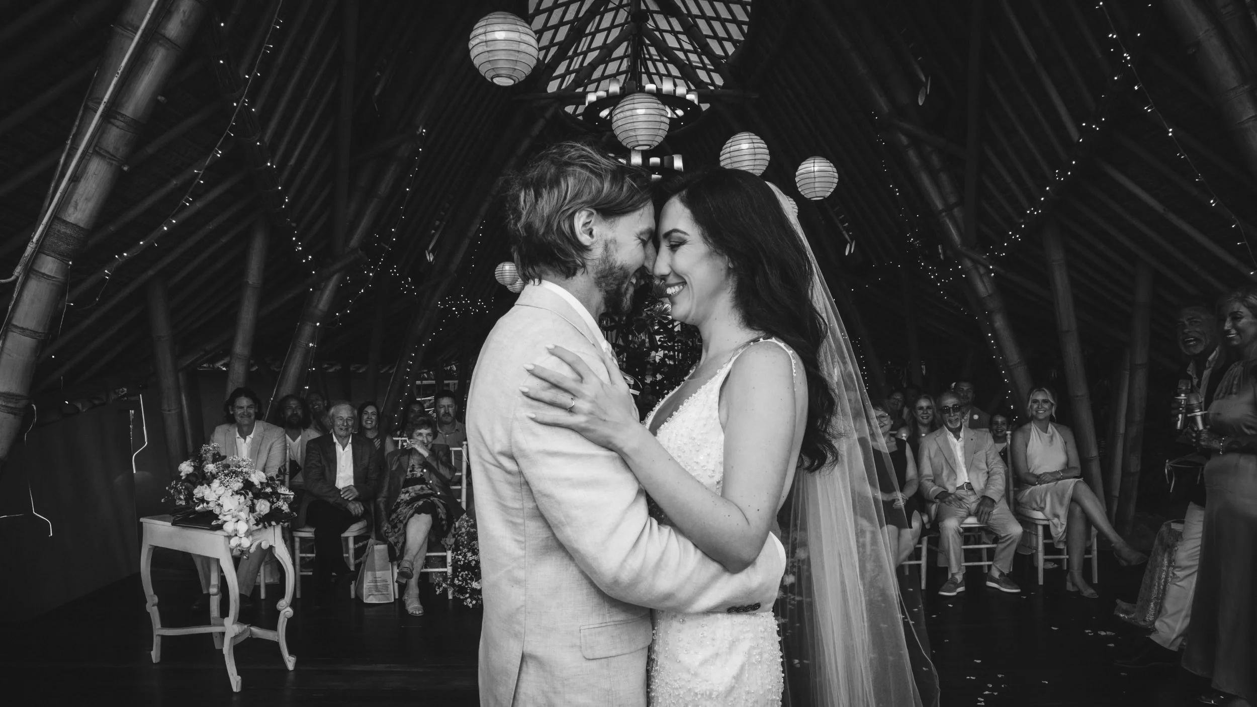 Luxury jungle wedding at Kanyon Ubud Bali — bride and groom exchange vows surrounded by their guests in bamboo structure.