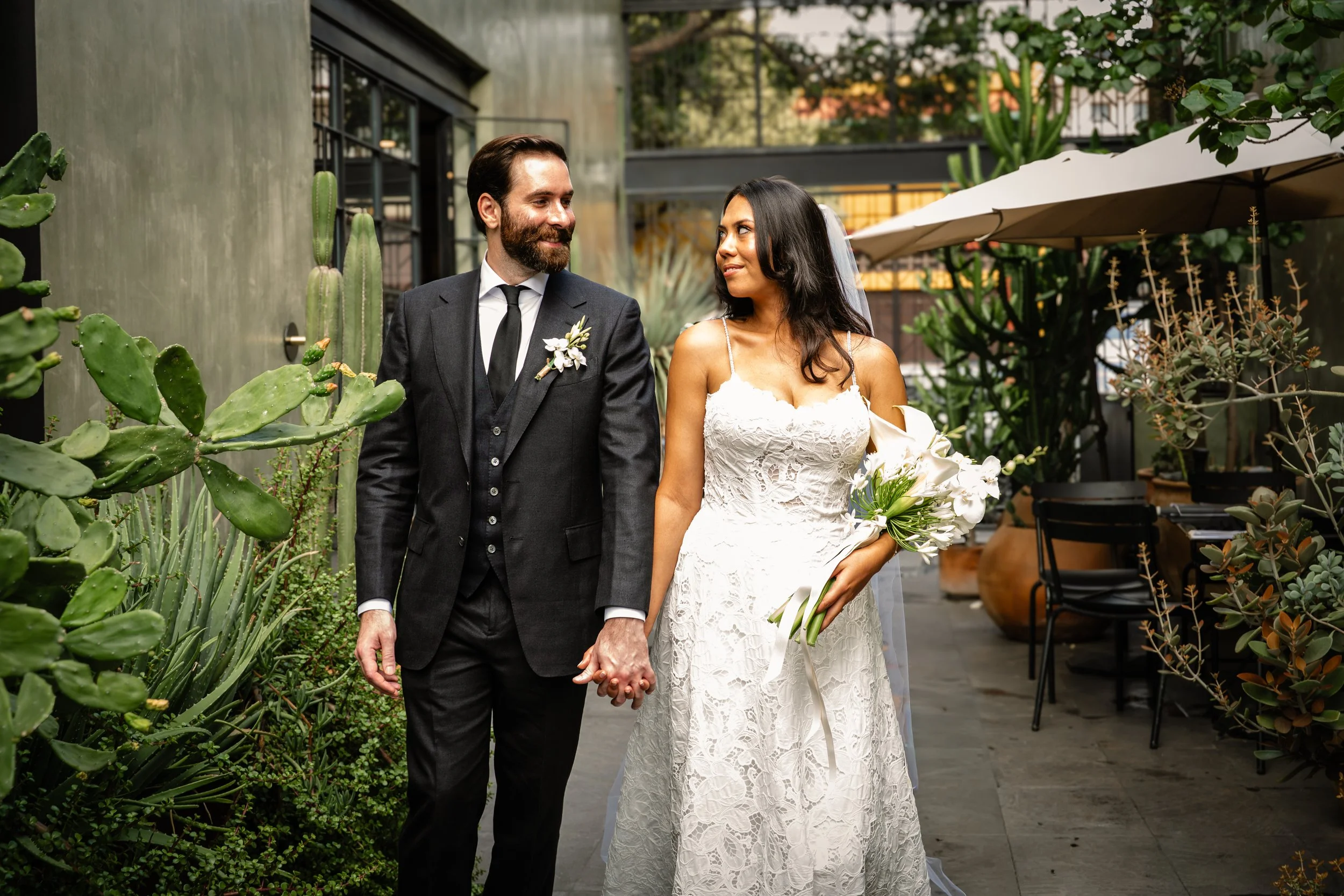 Maried couple in the center of Traditional Oaxacan courtyard with greens all around. Couple walking in the alley of their colorfull wedding. Oaxaca luxury wedding photography