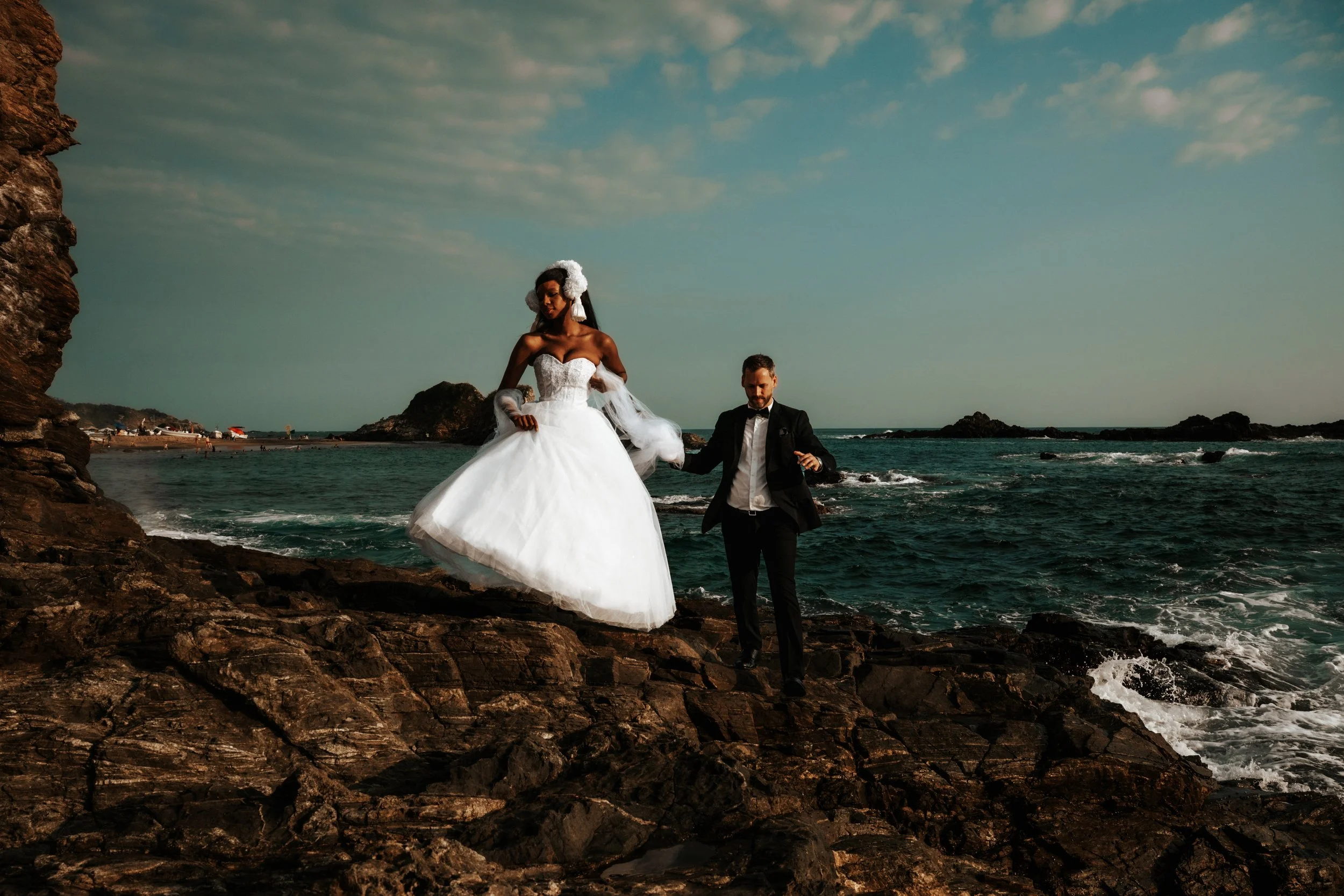 A destination wedding on the Oaxaca coast, captured with a documentary and emotion-driven approach that prioritizes presence over performance. Maried couple walking on rocks near mazunte beach with an elopement vibe.