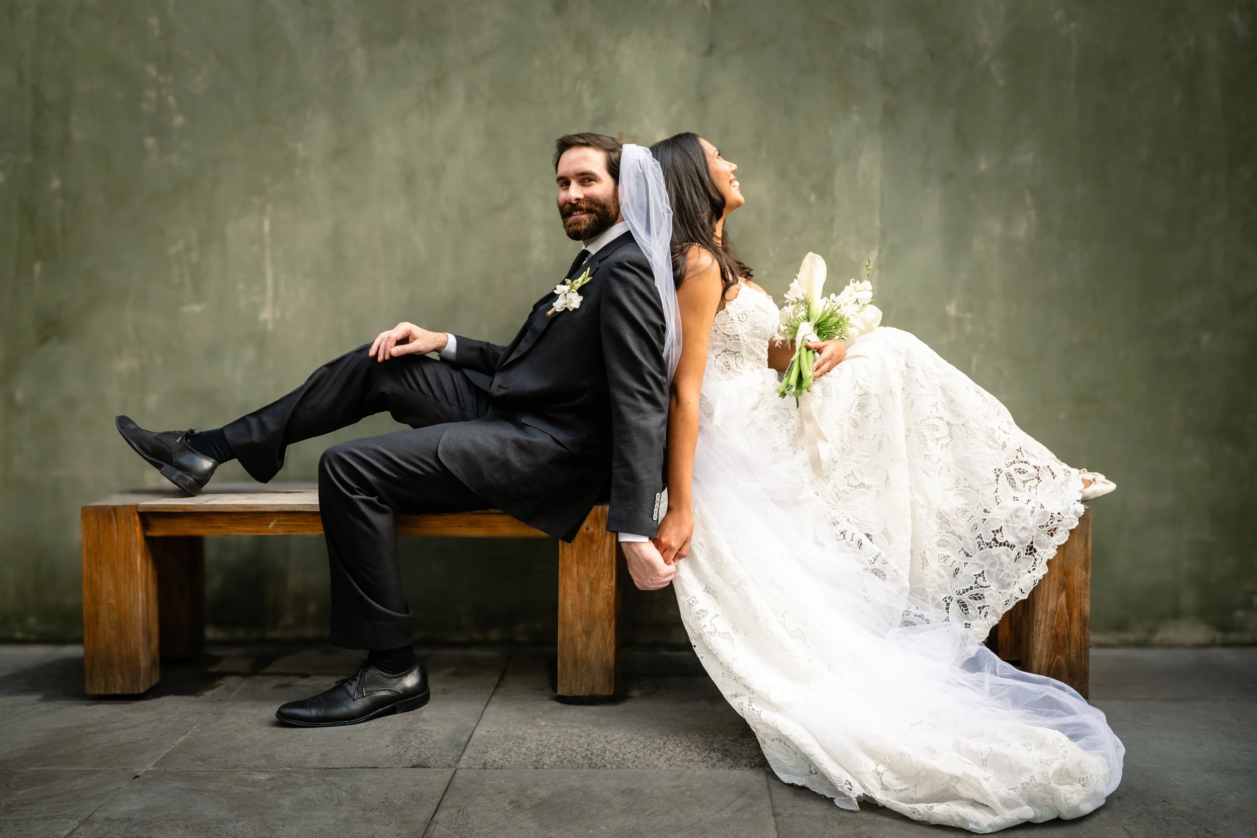 Maried couple in the center of Traditional Oaxacan courtyard seated in a banch. Oaxaca luxury wedding photography