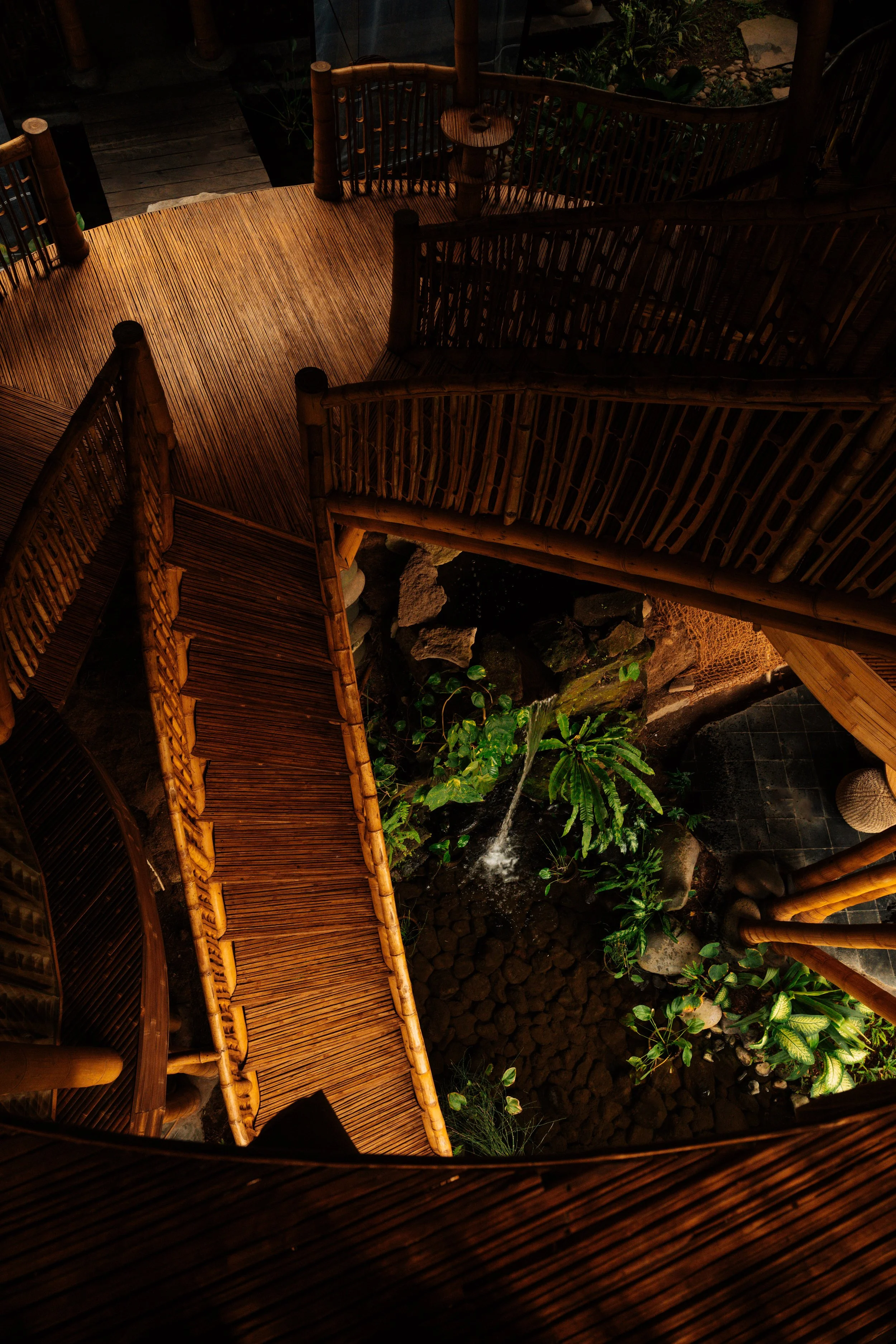 Suspended walkway connecting Villa Kelapa's spaces through the Balinese jungle. Bamboo architectural detail, natural light, Green Village Bali.
