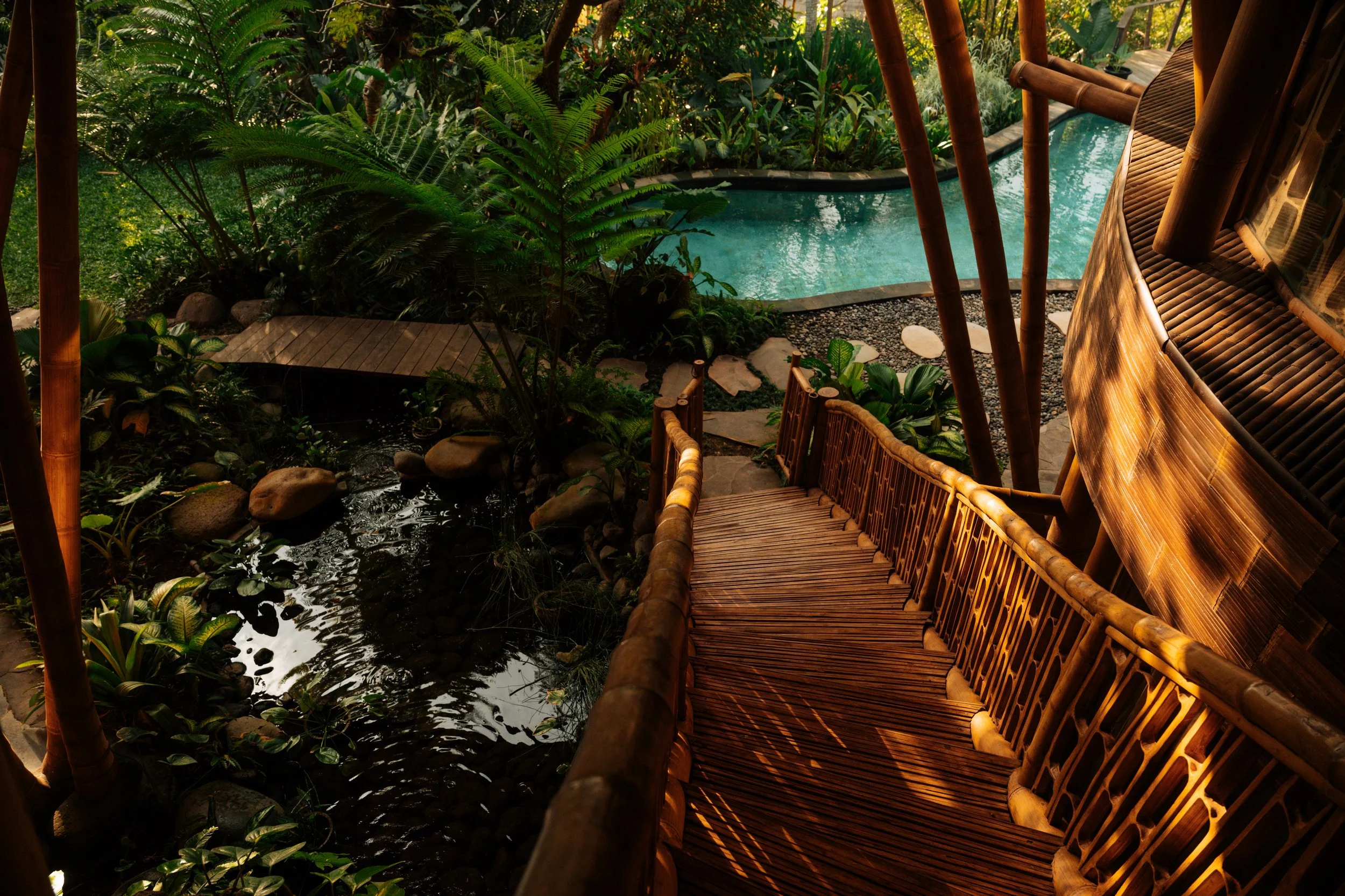 Suspended walkway connecting Villa Kelapa's spaces through the Balinese jungle. Bamboo architectural detail, natural light, Green Village Bali.