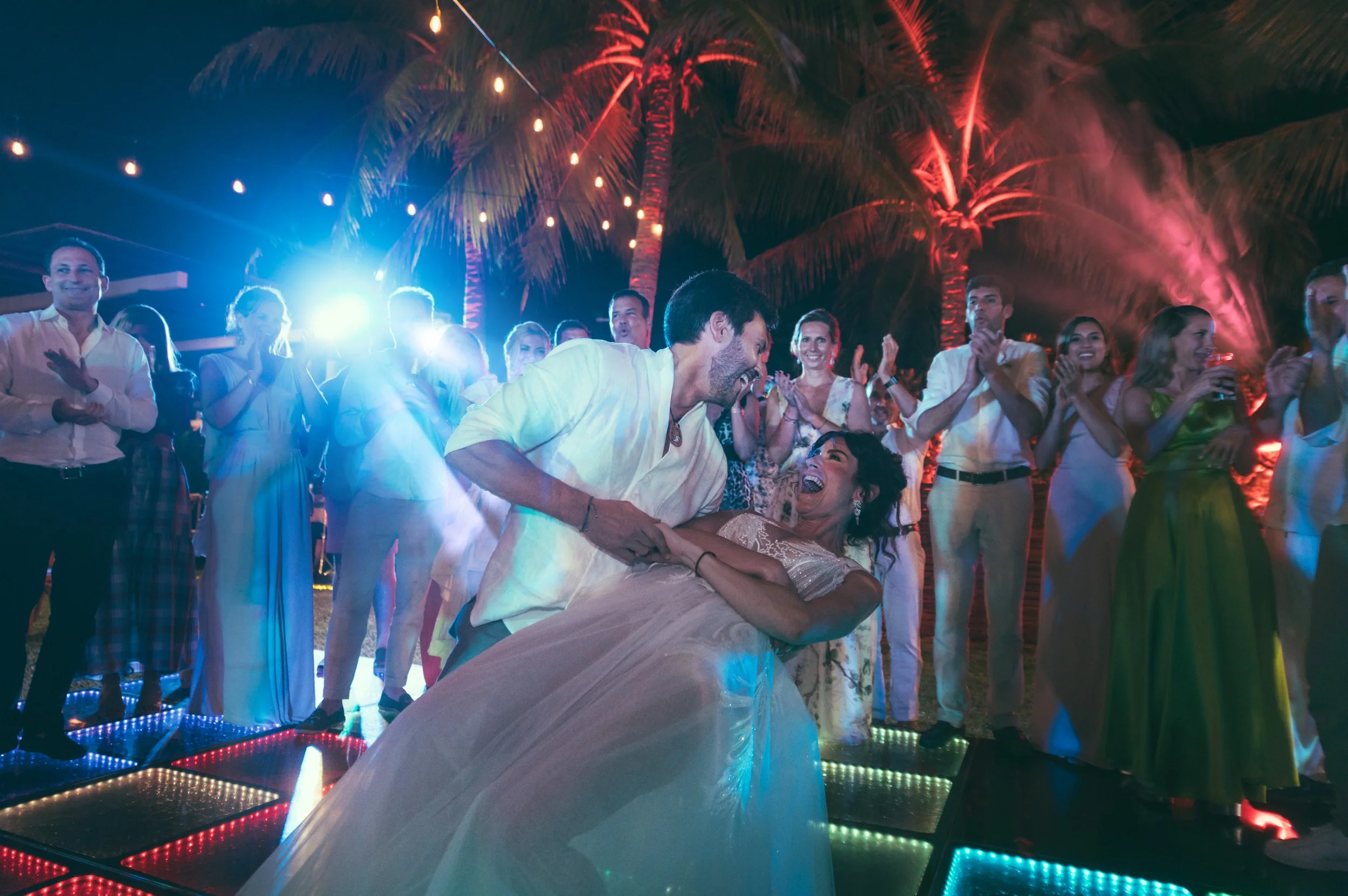 Maried couple dancing in their wedding party in the middle of the dancing floor with all their guest around them. Very happy vibes and colorfull. nice light beam in luxurious Villa in Puerto Escondido