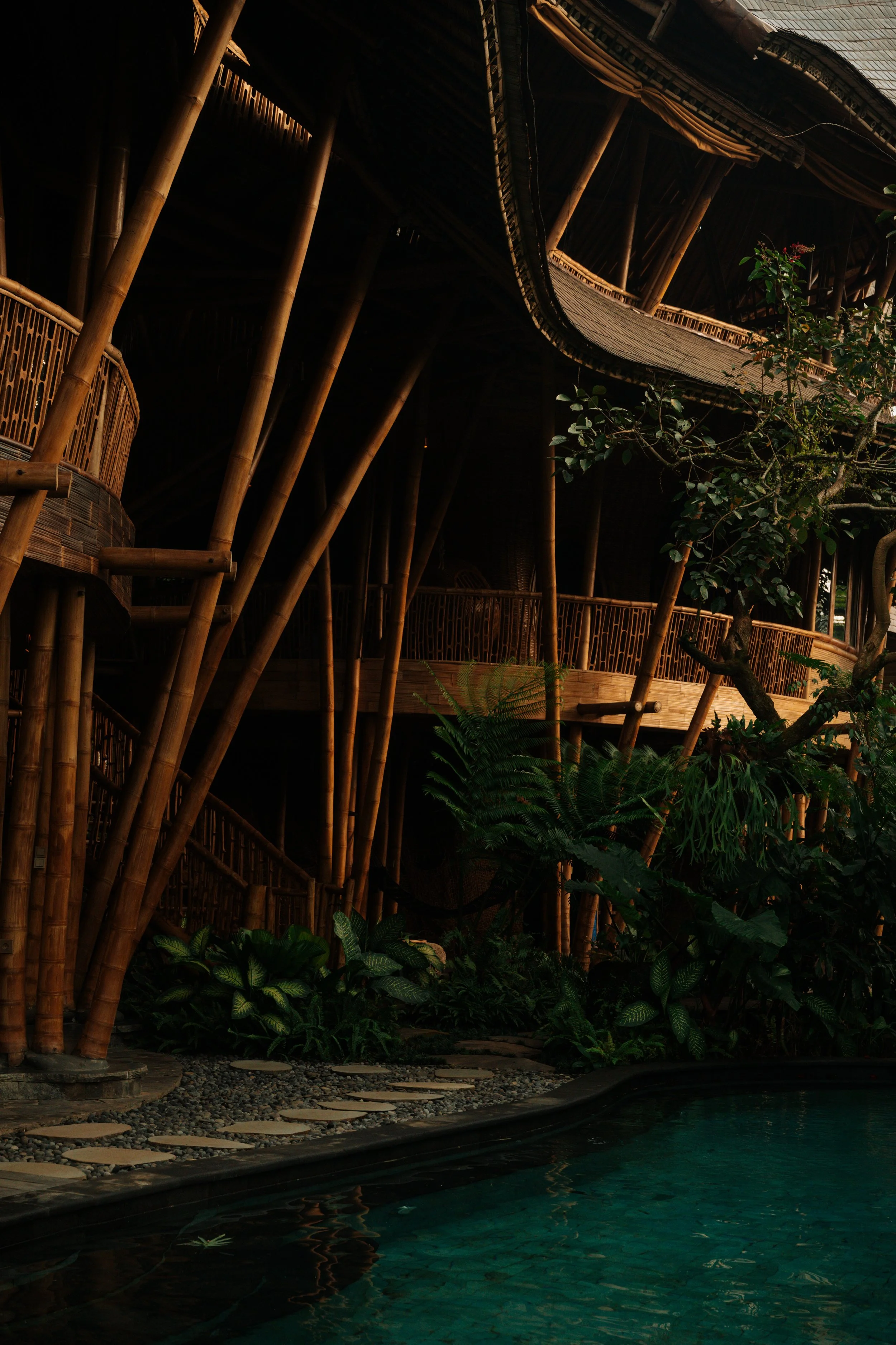 Stone pathway through tropical garden, Villa Kelapa, Bali. Sustainable bamboo architecture surrounded by lush vegetation, Green Village.
