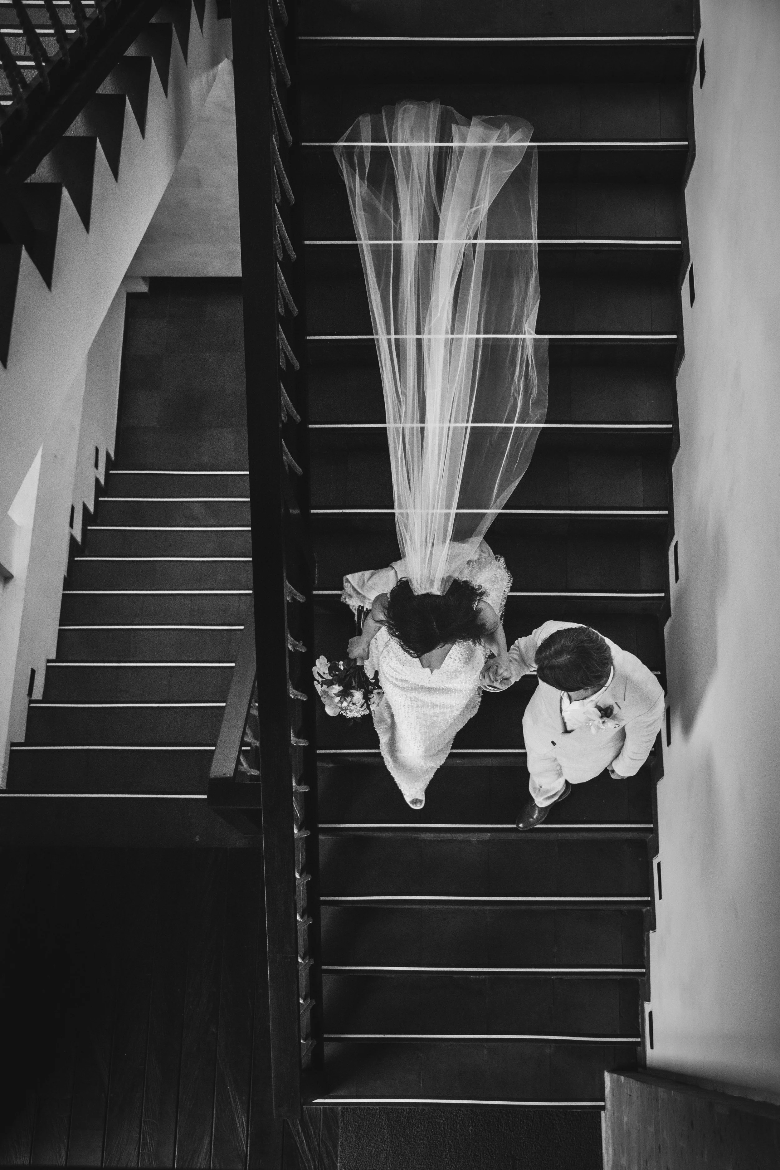Bali jungle wedding staircase — bride and groom running hand-in-hand down a stone staircase framed by dense rainforest, Kanyon Ubud villa resort.