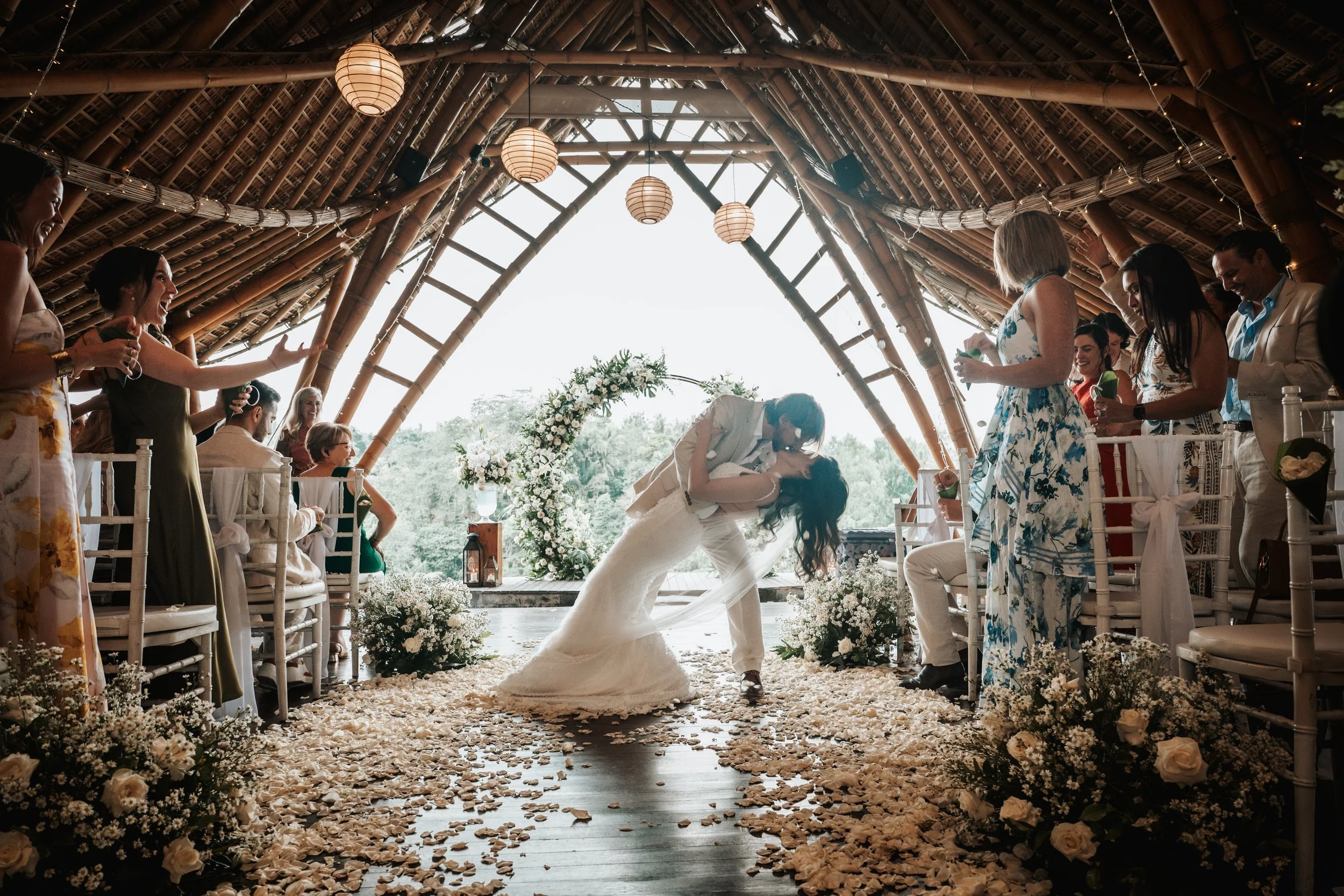 Bamboo wedding chapel Bali — couple exchanging kiss inside a striking bamboo church, natural architecture framed by Ubud's jungle setting at Kanyon resort.