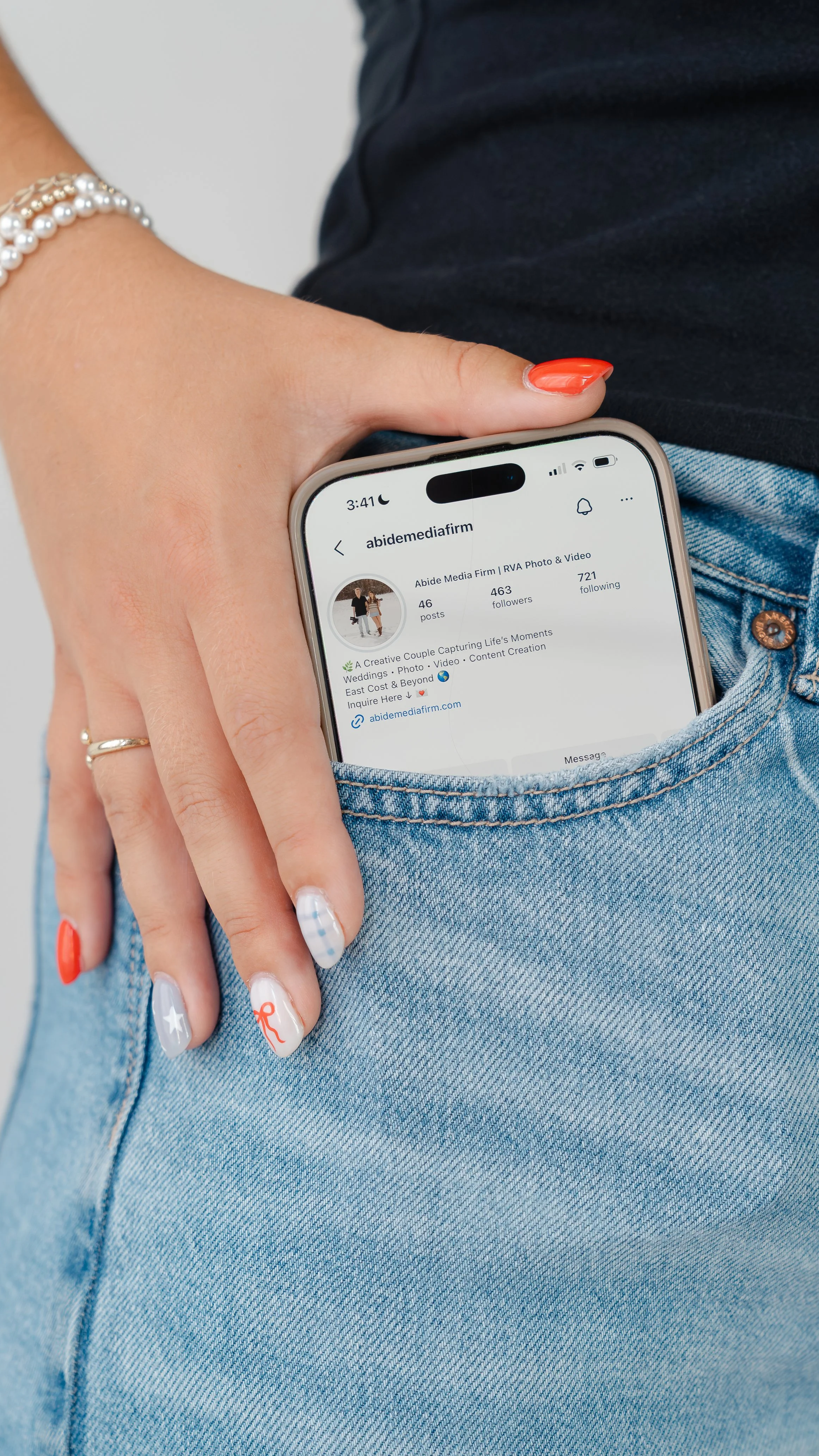 A person's hand holding a smartphone with an Instagram post open, showing a post titled 'PRE-TAN INSTRUCTIONS' from the account @thesunkissedsociety_.