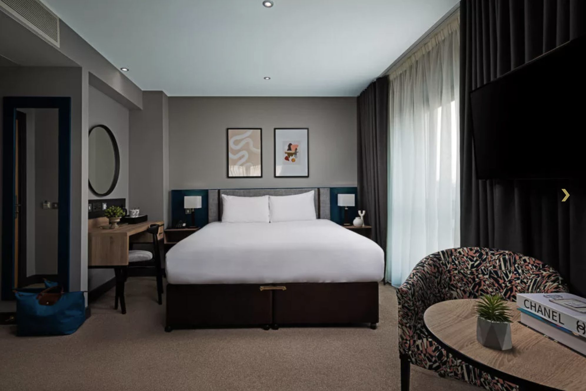 One of the hotel’s luxurious suites, featuring a large king bed covered in crisp white linen.