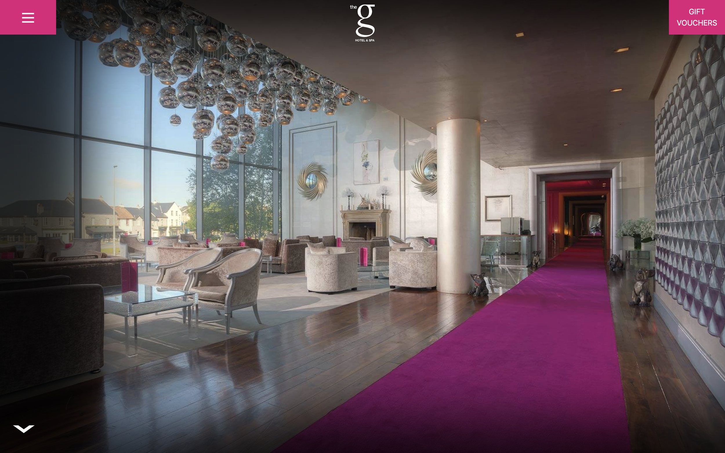 Interior view of 5 star hotel with large glass windows, silver chandelier and bright pink carpet.