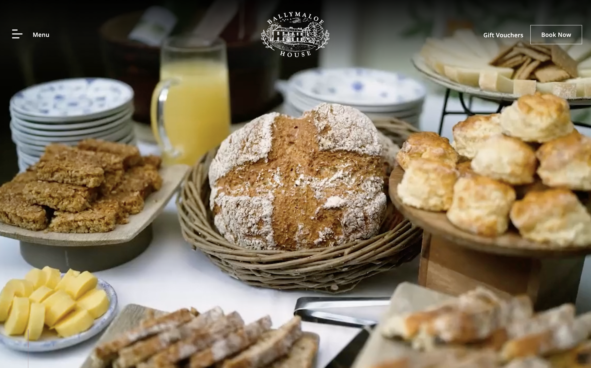 A display of breakfast items including a loaf of bread, cheese slices and a pitcher of orange juice.