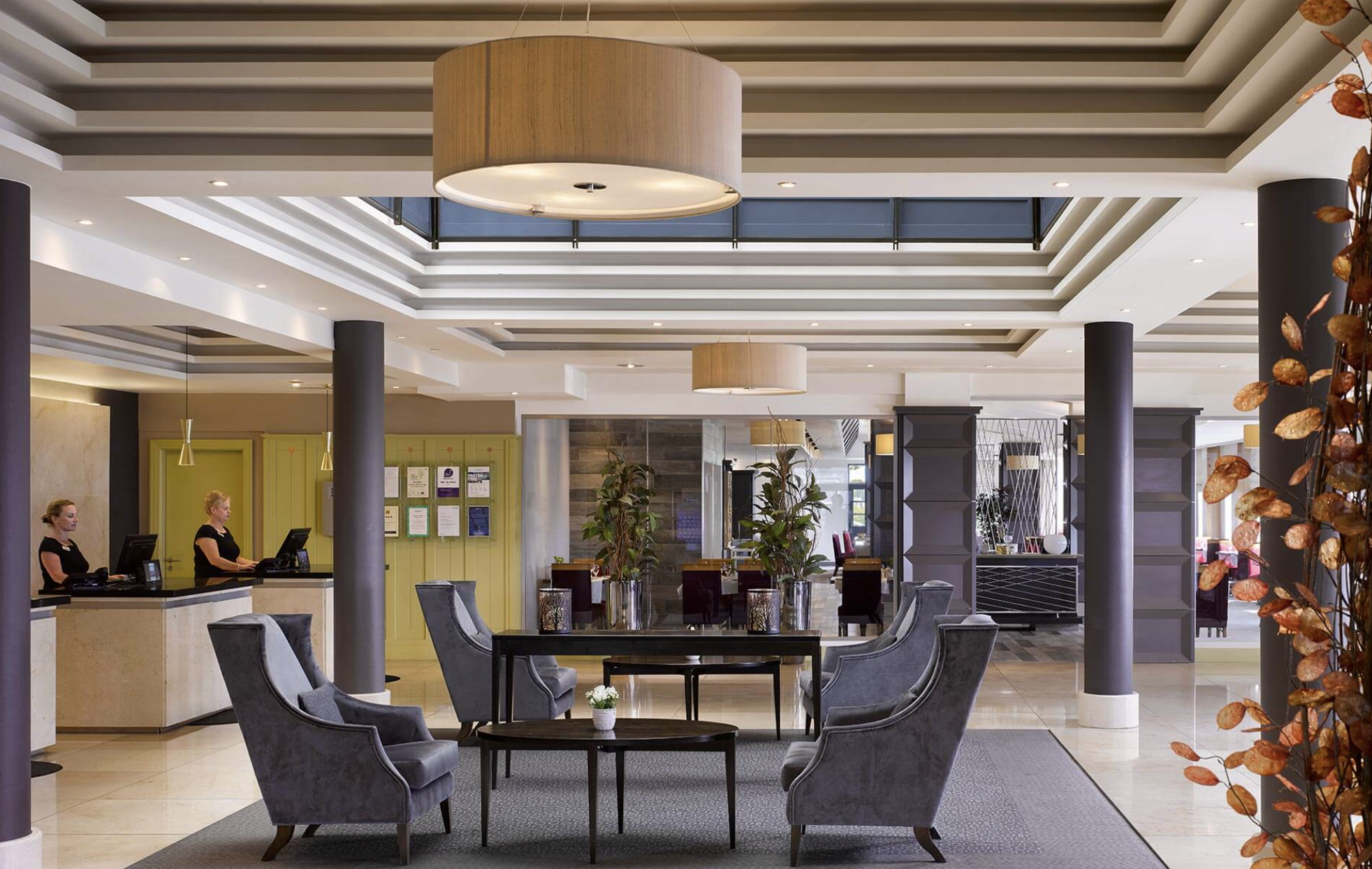 Bright, spacious Radisson Blu Sligo lobby with four large blue velvet chairs and mahogany tables.