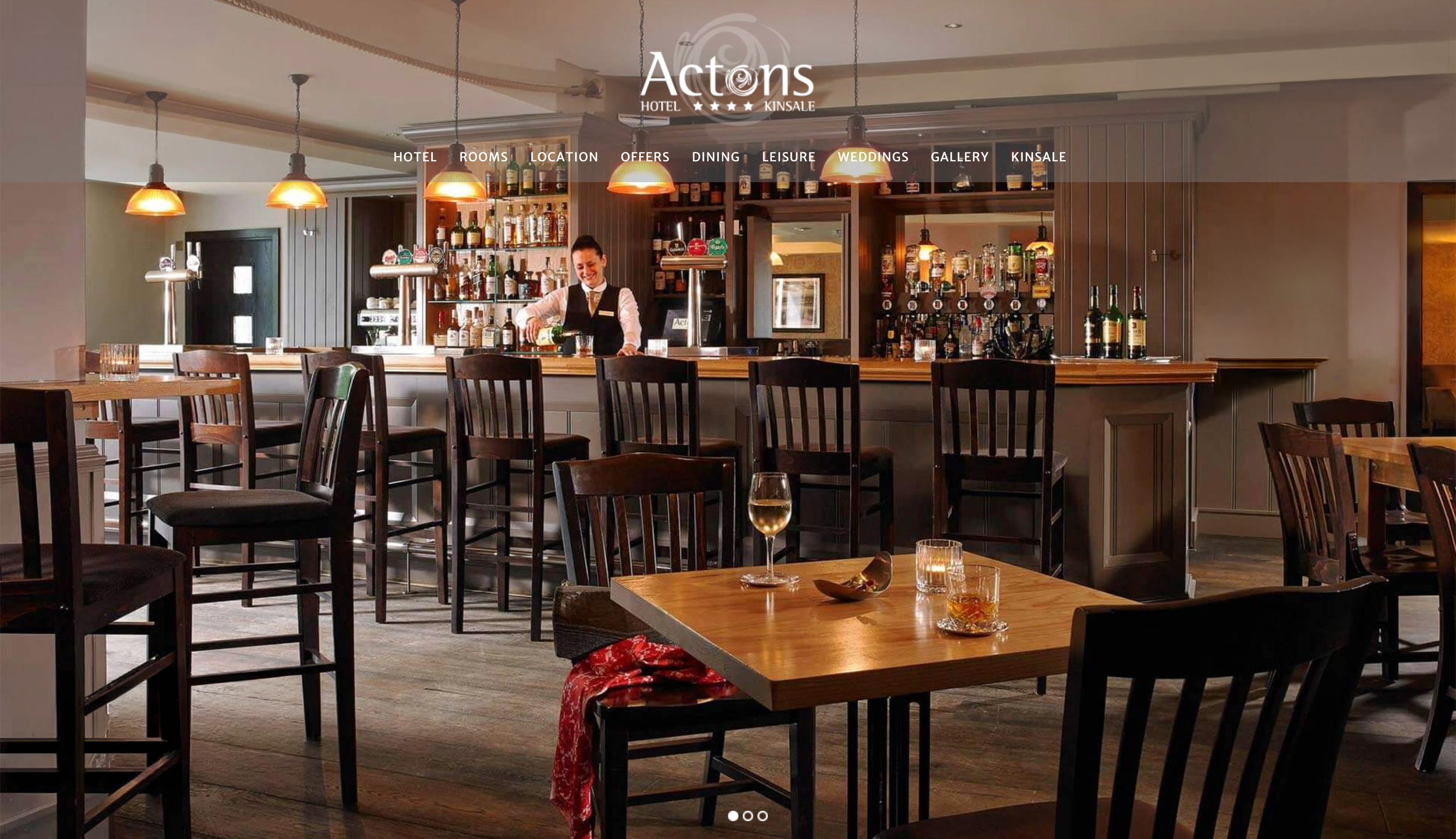 The spacious lounge area with a barmaid pouring a glass of Irish whiskey behind the long bar.