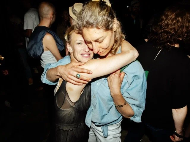 Two women hugging warmly at a social gathering or party.