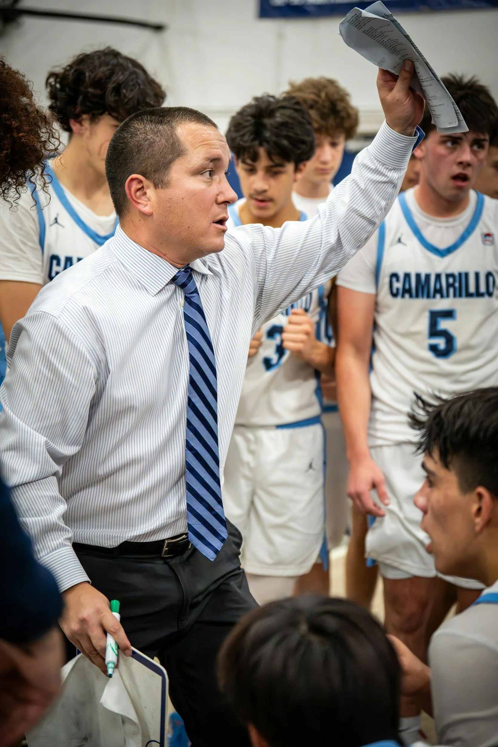 Coach speaking to basketball team in locker room, players listening attentively