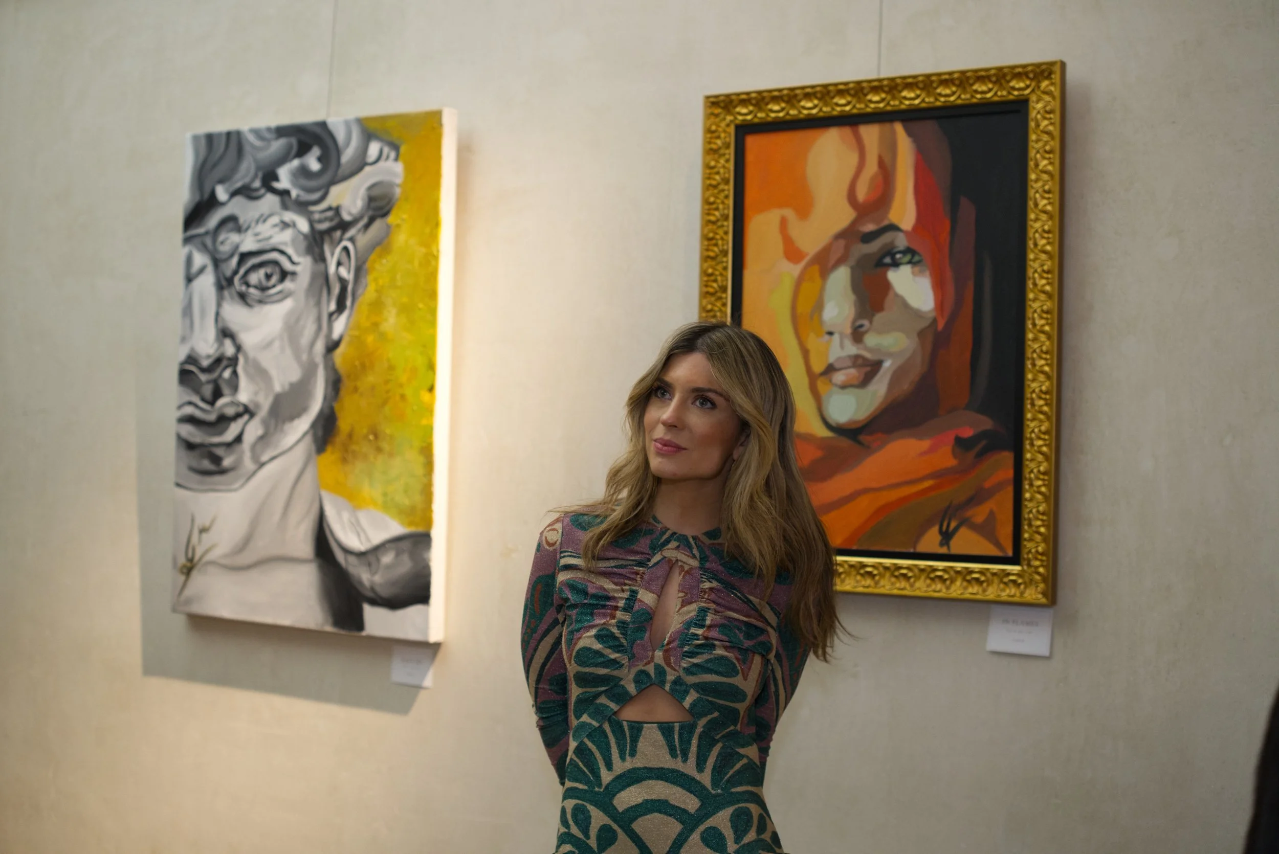 Mujer en una galería de arte observando dos pinturas en la pared.